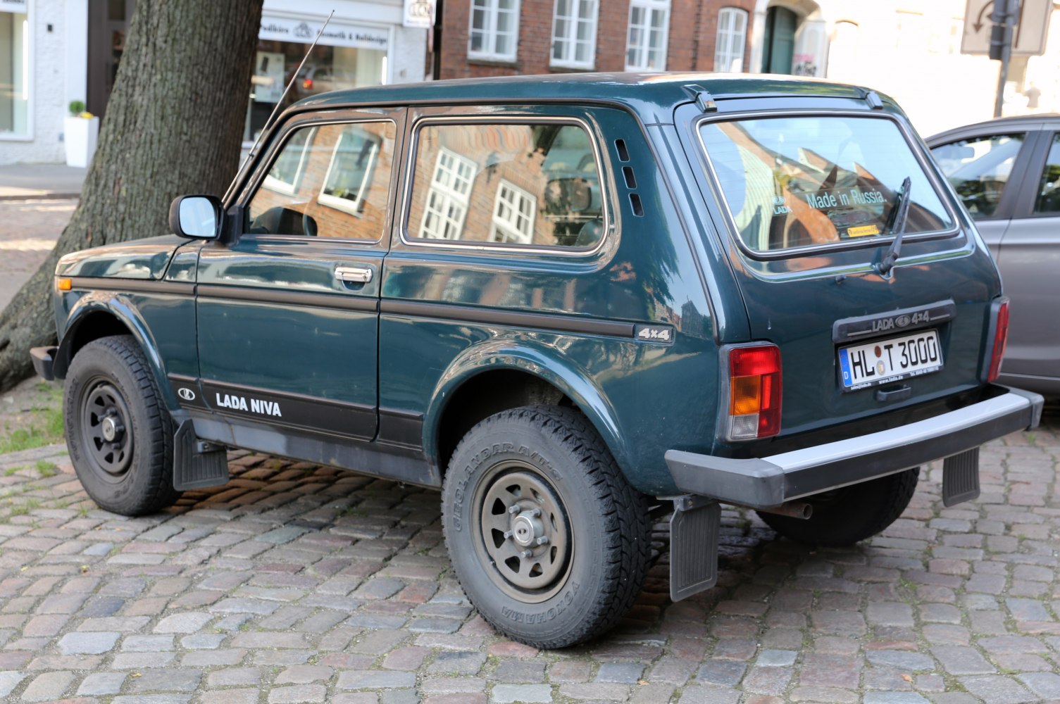 Rear side view of compact 3-door SUV with rugged tires on cobblestone.