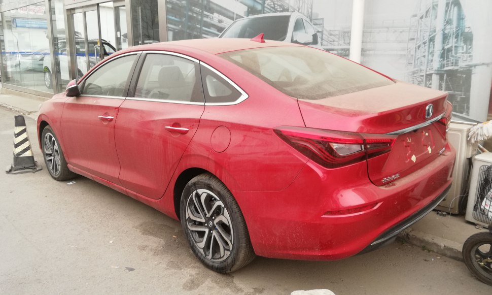 Red mid-size sedan rear view with sleek tail lights and alloy wheels