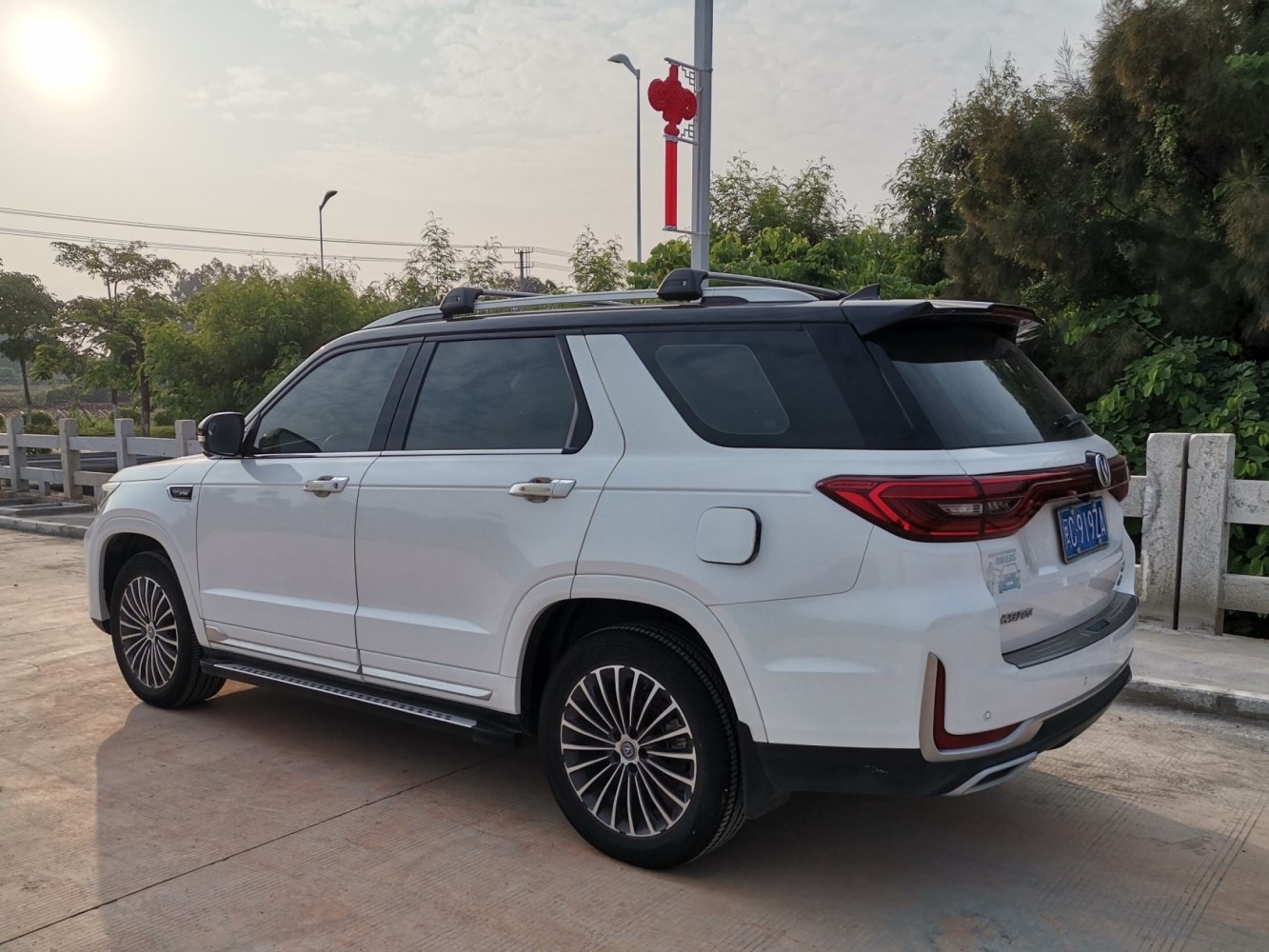 Rear side view of white SUV with black roof and unique taillights