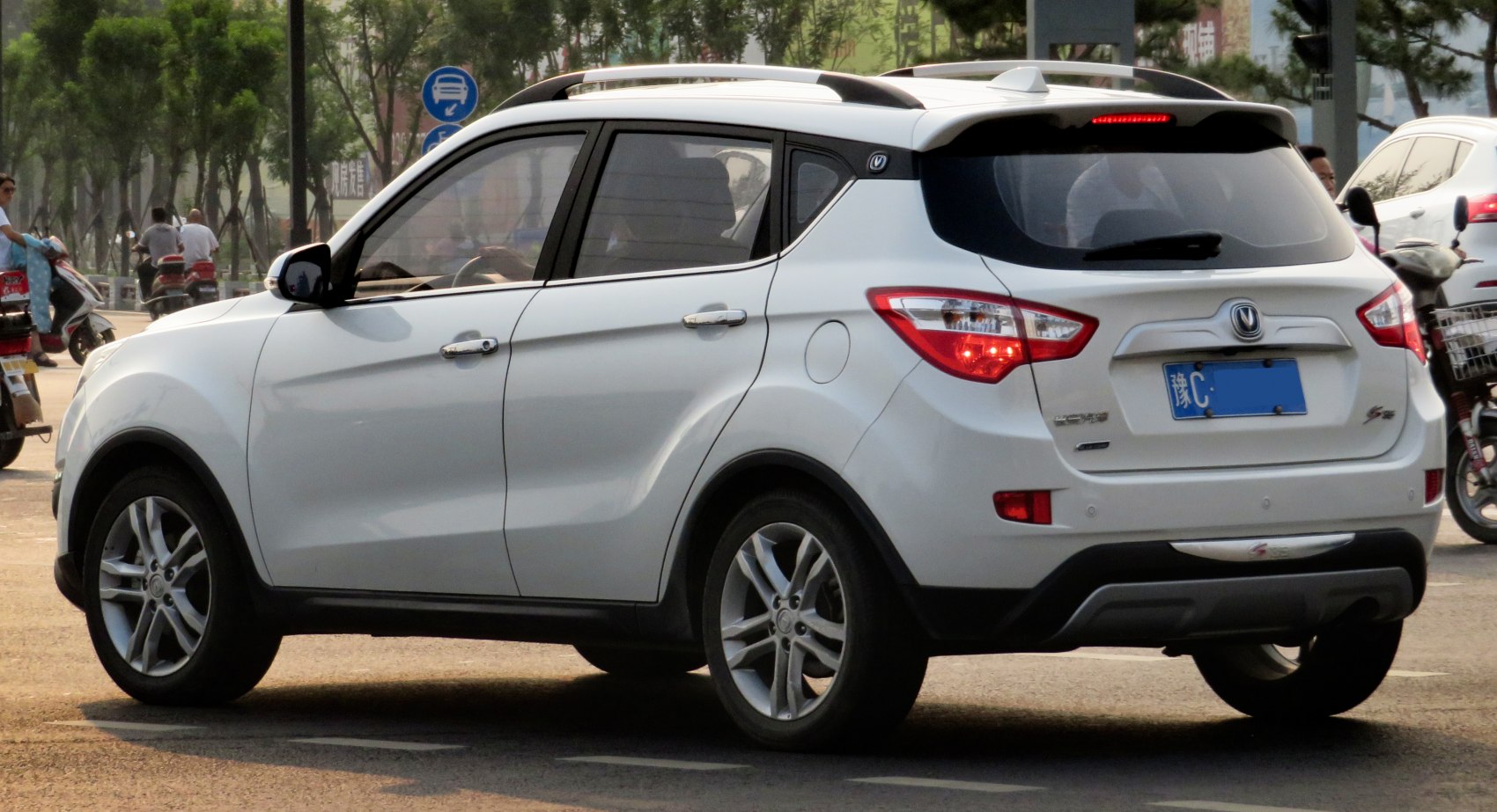 Rear side view of white compact SUV with roof spoiler and alloy wheels
