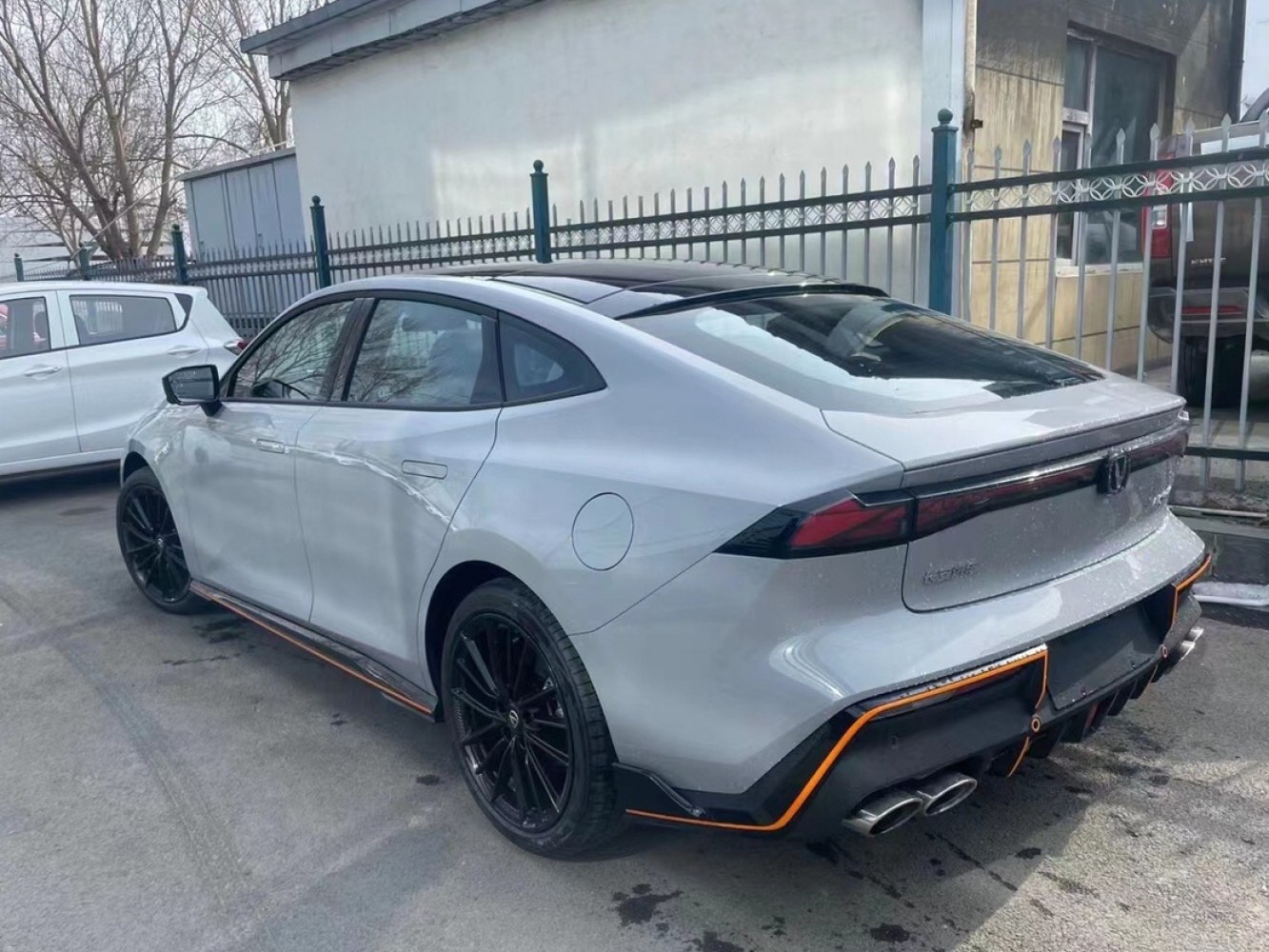 Rear quarter of sporty sedan with quad exhausts and black wheels