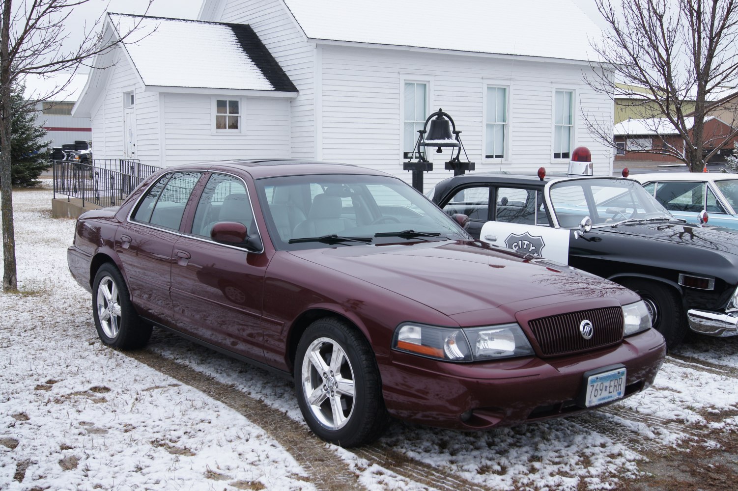 Front side view of a sedan with alloy wheels in a snowy setting
