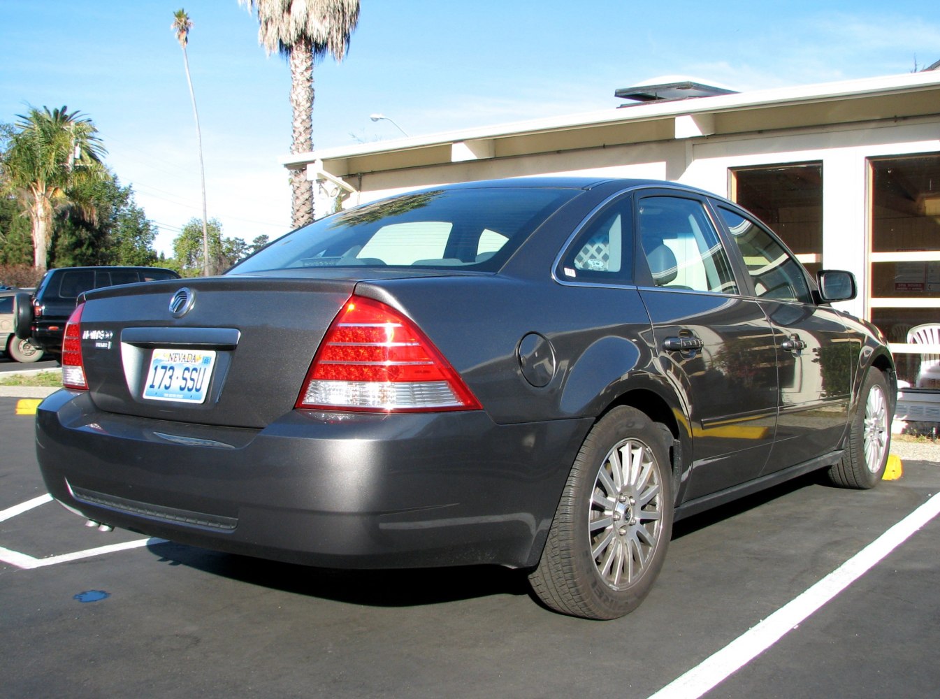 Rear and side view of a dark sedan with distinctive tail lights and alloy wheels