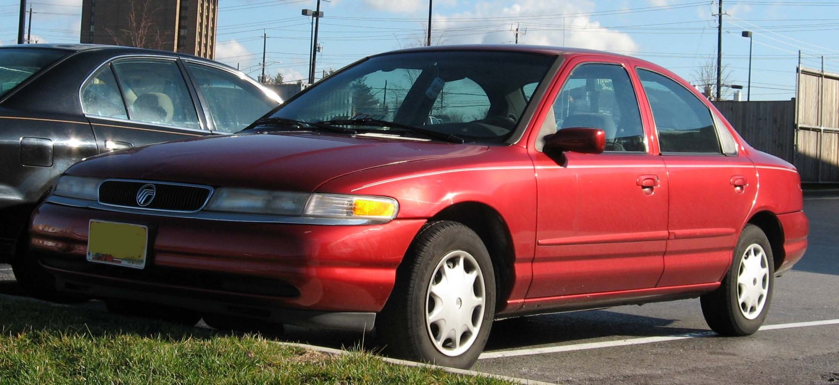 Red mid-1990s sedan with rounded headlights and smooth body lines