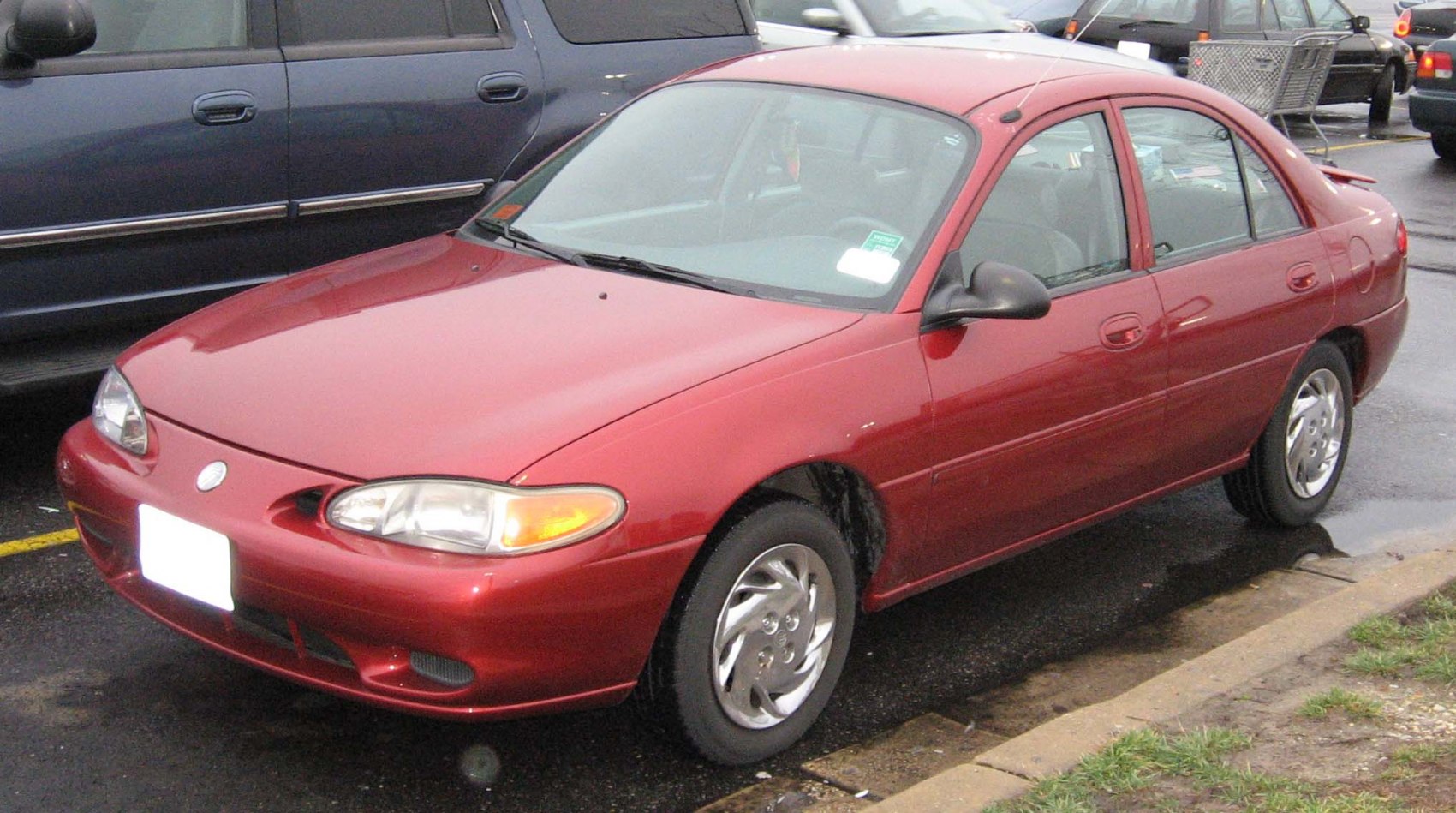Red compact sedan with rounded headlights and smooth body lines, front-side angle