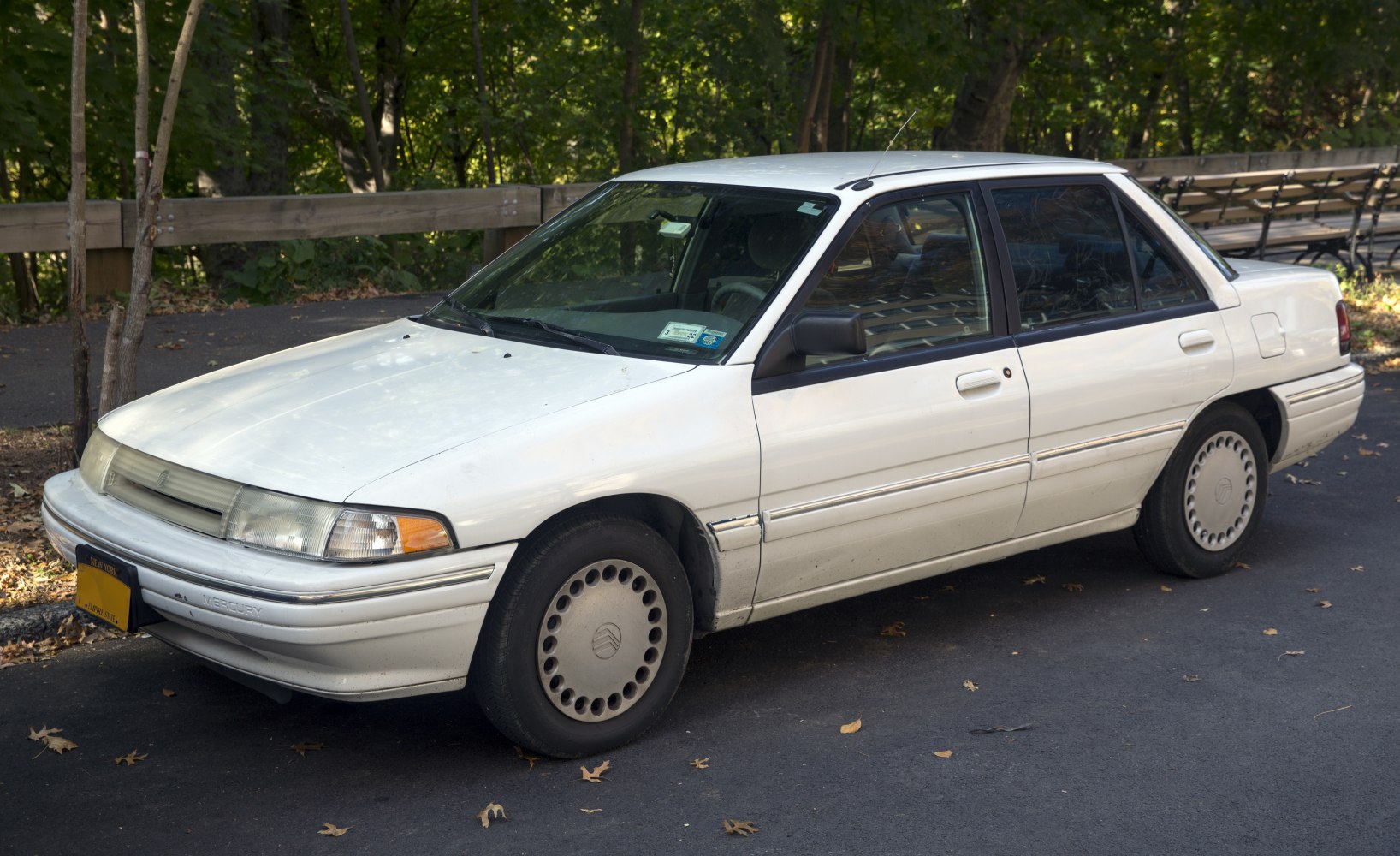 White four-door sedan with front and side view in outdoor setting