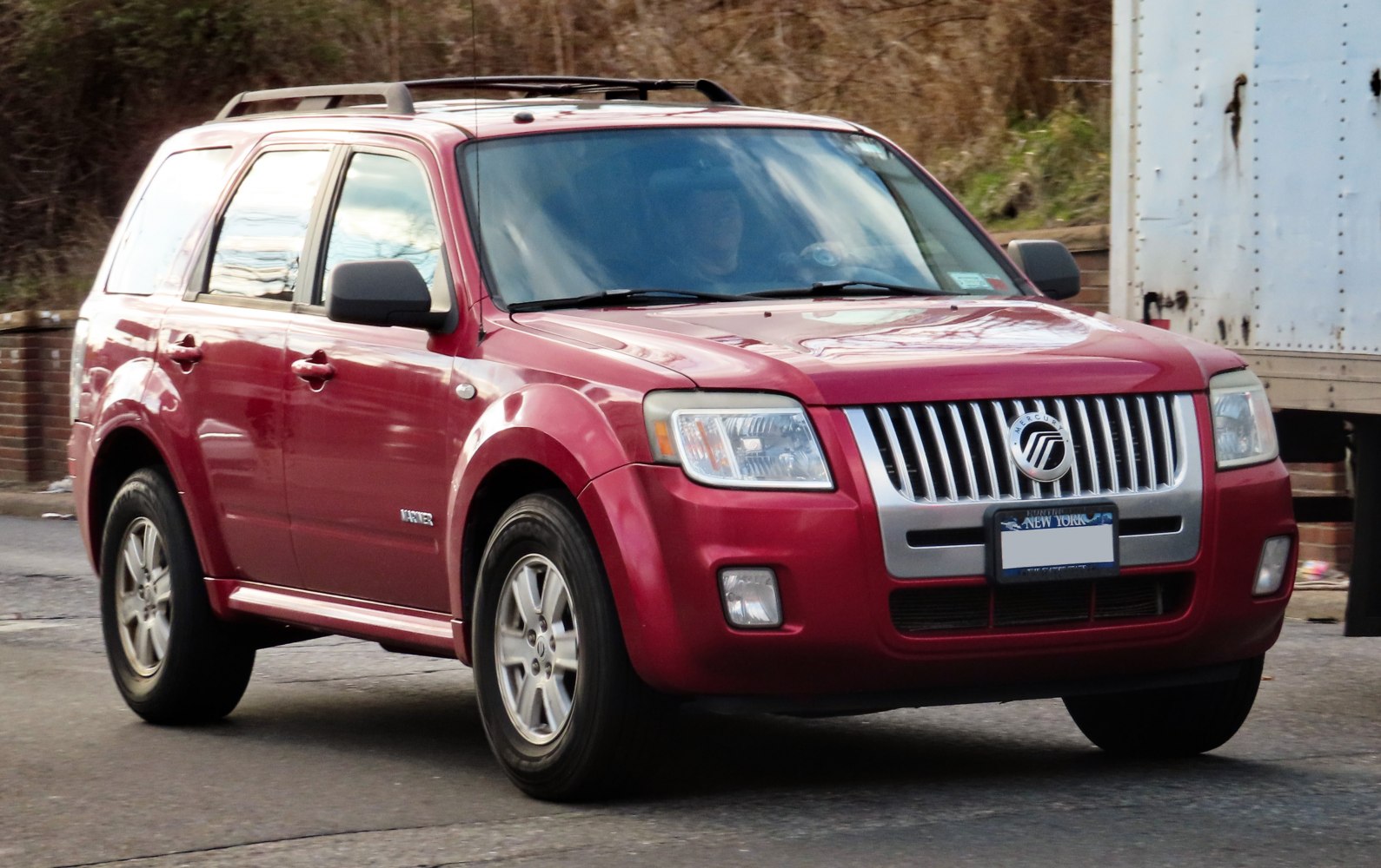 Red SUV with chrome vertical grille and roof rails
