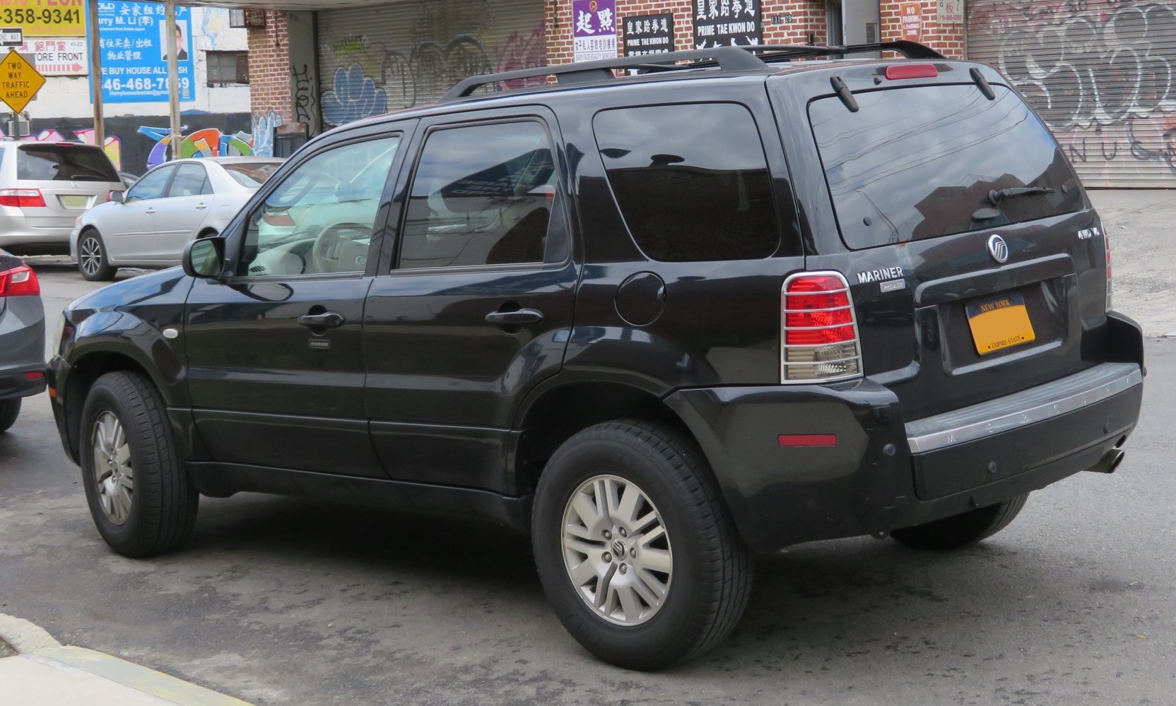 Rear side view of black SUV with roof rails and distinctive taillights