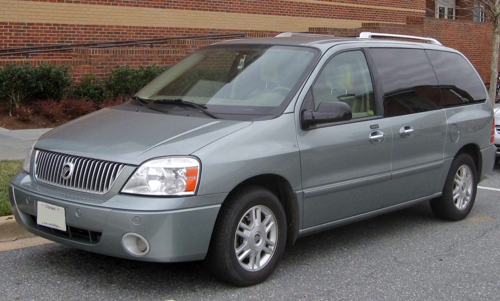 Silver minivan with grille and large windows, front side view