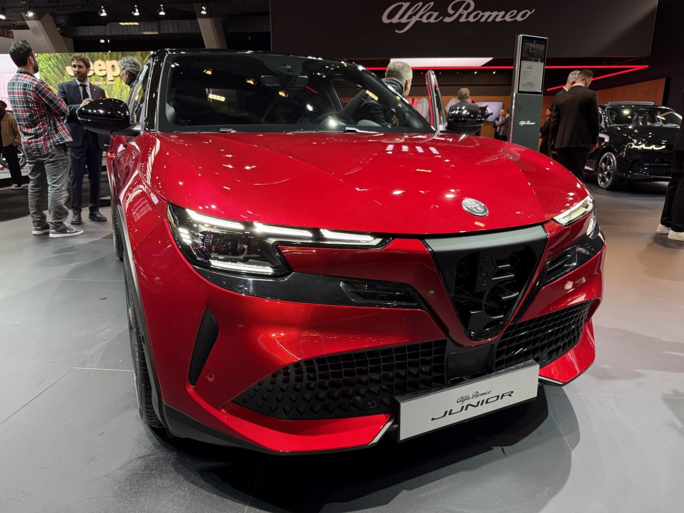 Sleek LED headlights and signature Alfa Romeo triangular grille on red vehicle front.