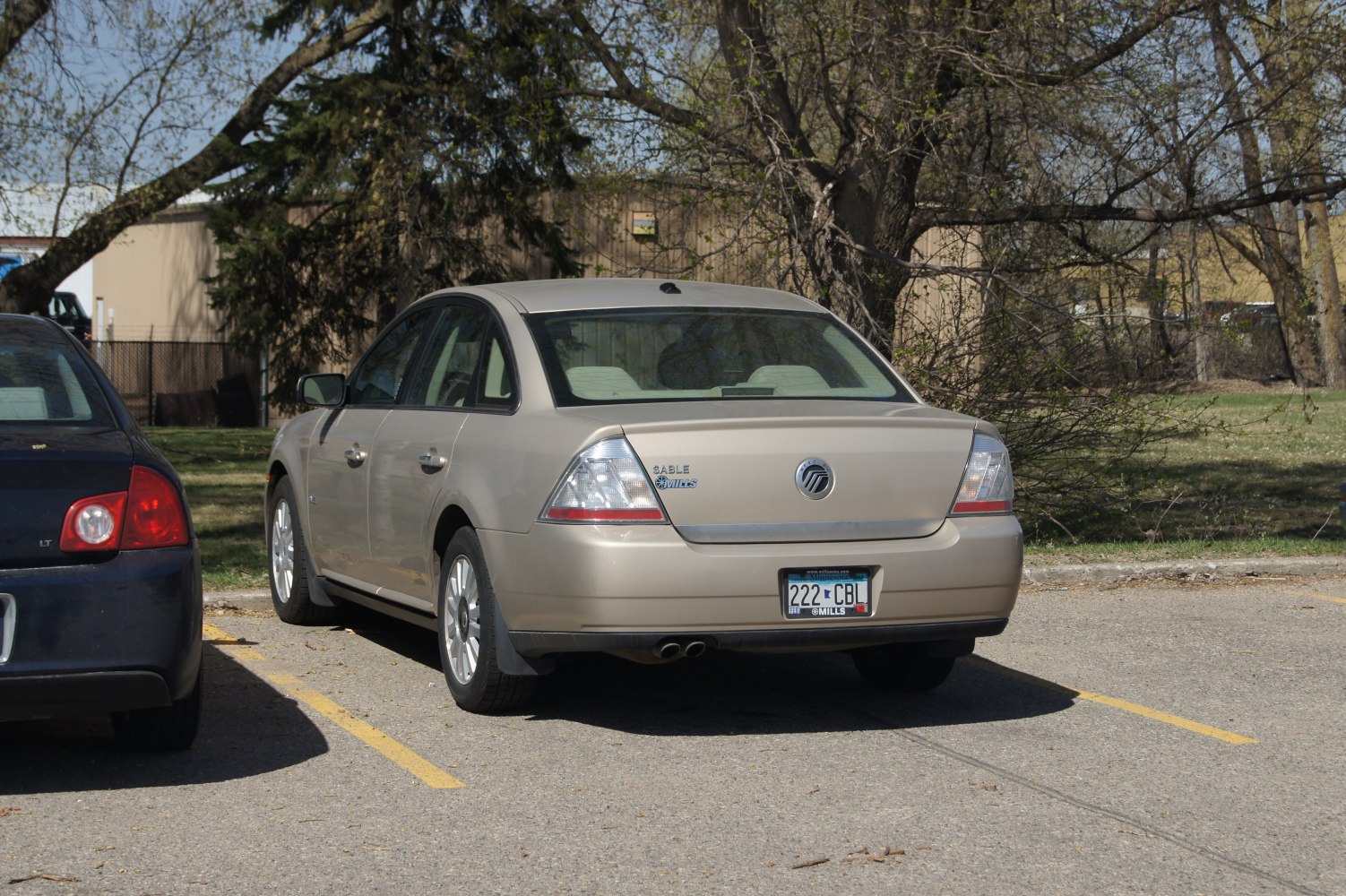 Rear view of a beige sedan featuring distinctive triangular tail lights and dual exhaust tips