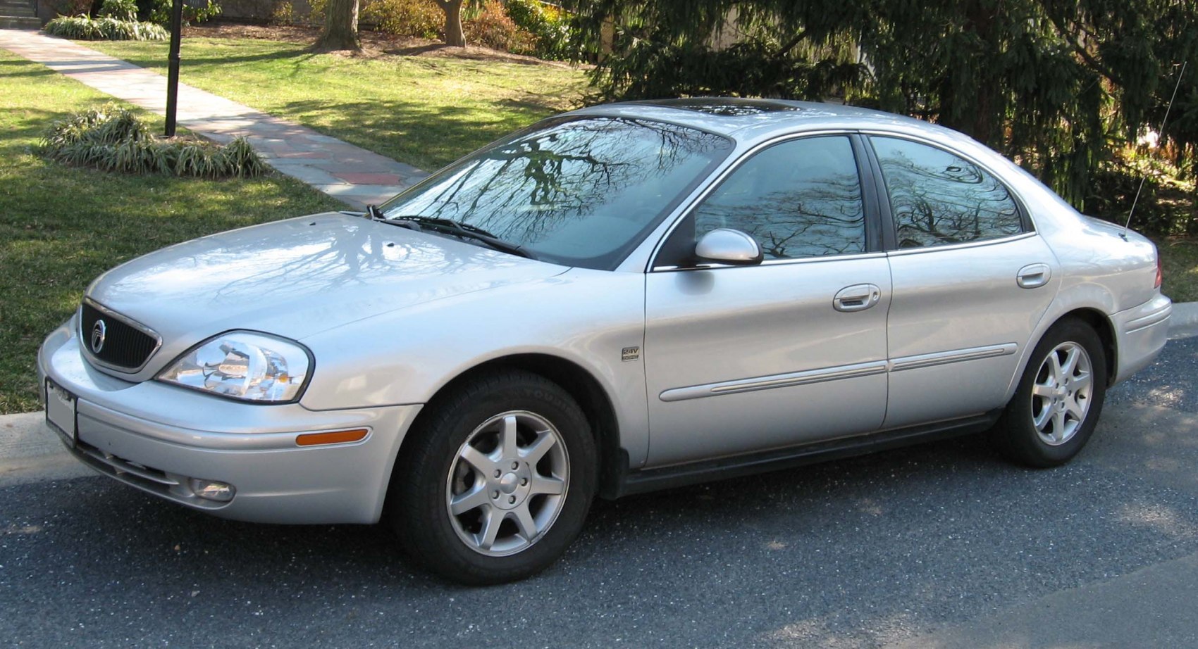 Silver sedan with alloy wheels and chrome trim, side view on street