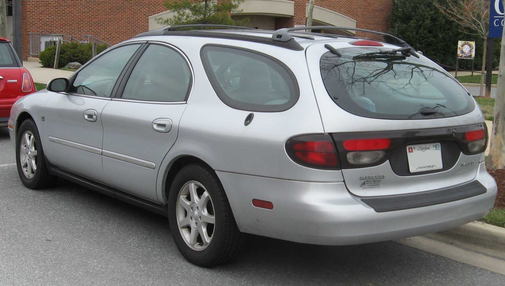 Silver midsize station wagon rear and side with roof rails and unique rear window