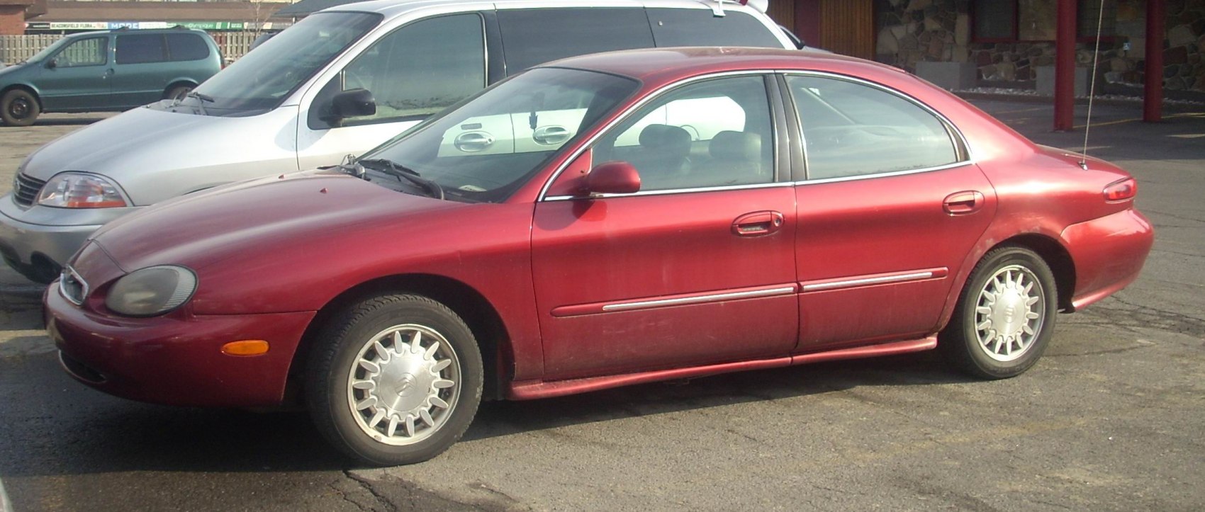 Side profile of red sedan with round headlights and alloy wheels
