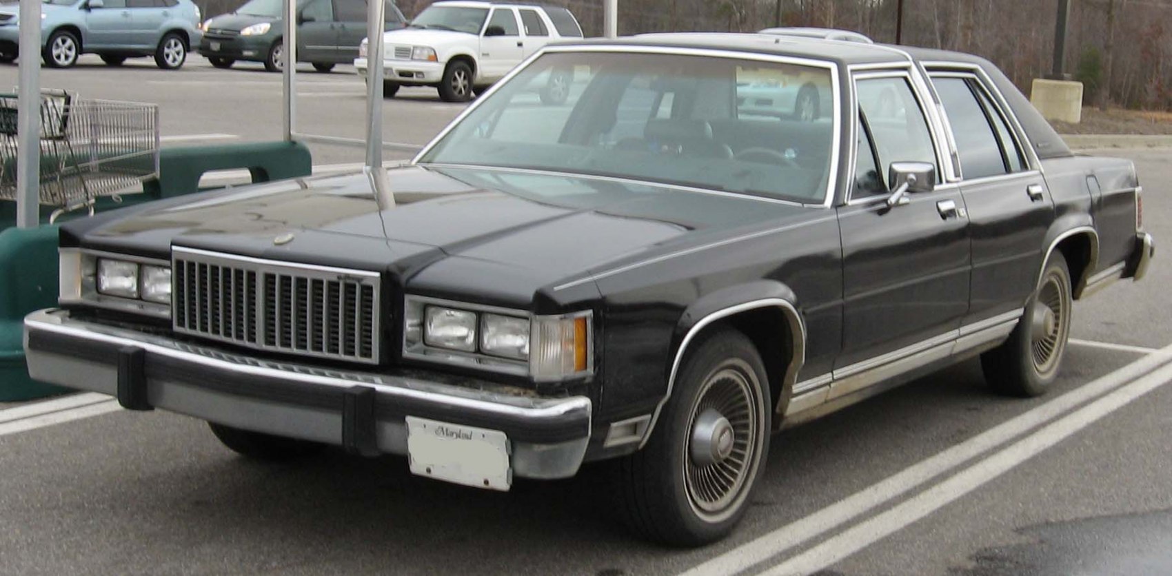 Large front grille with rectangular headlights and vintage wire-spoke wheels.