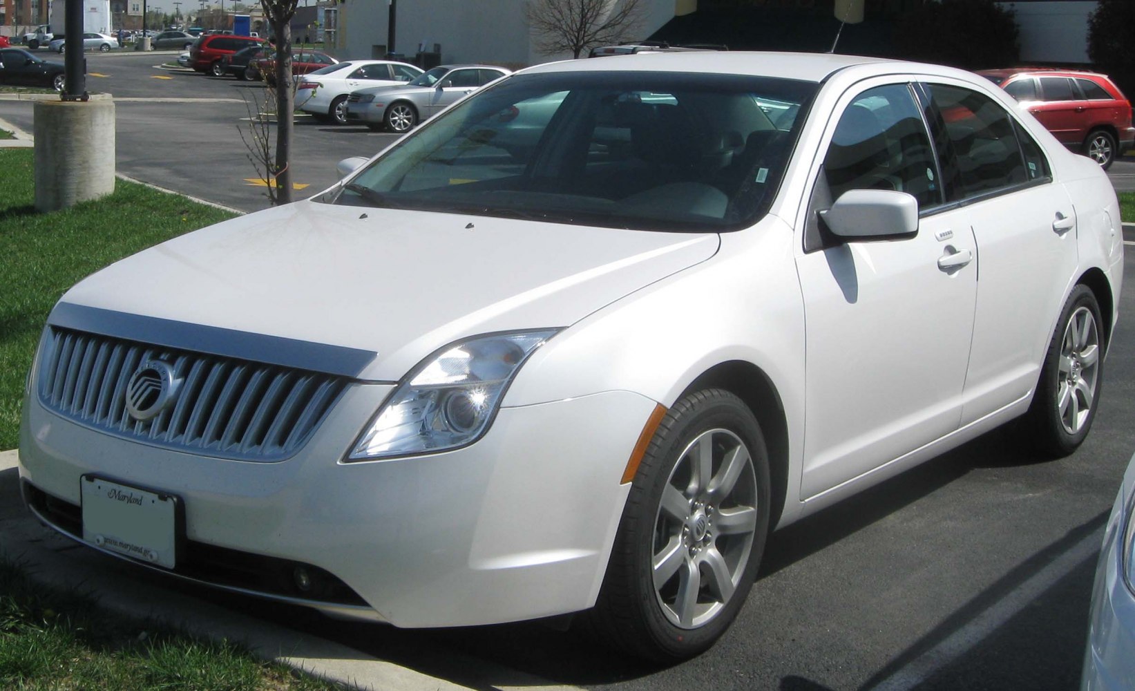 White sedan with vertical grille and alloy wheels, front side perspective.