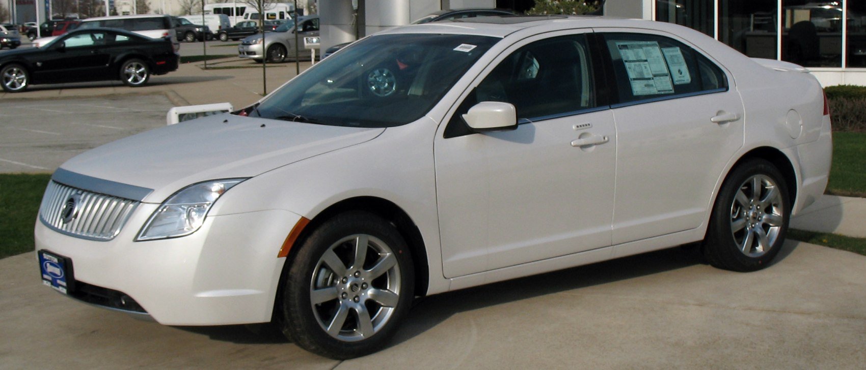 White sedan with chrome vertical slat grille and alloy wheels front-side view