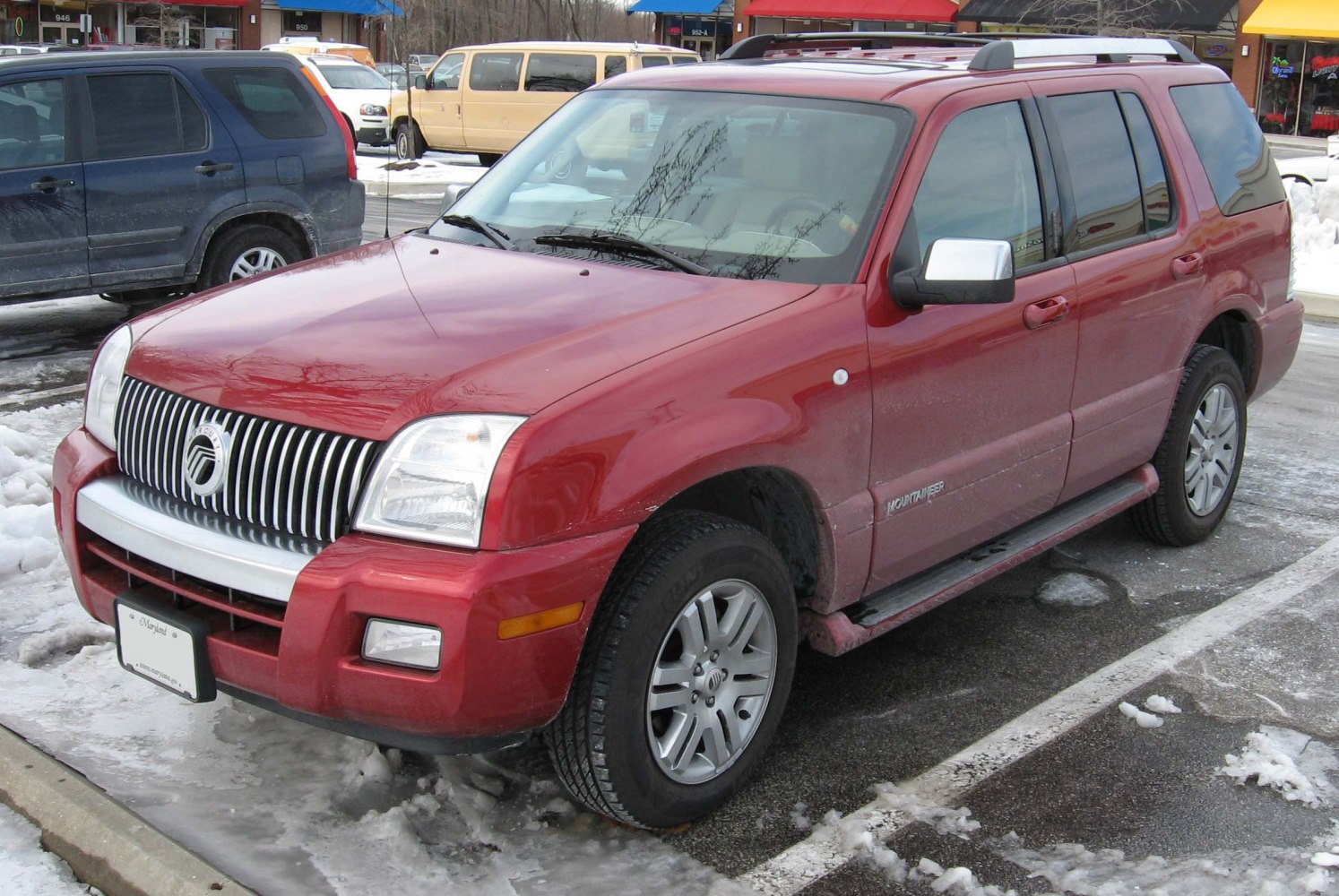 Front side view of red SUV with running boards and roof rails