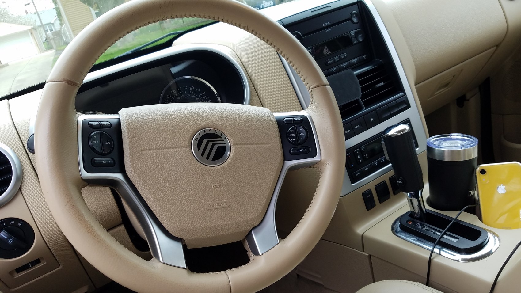Beige leather steering wheel with control buttons and gear shift console