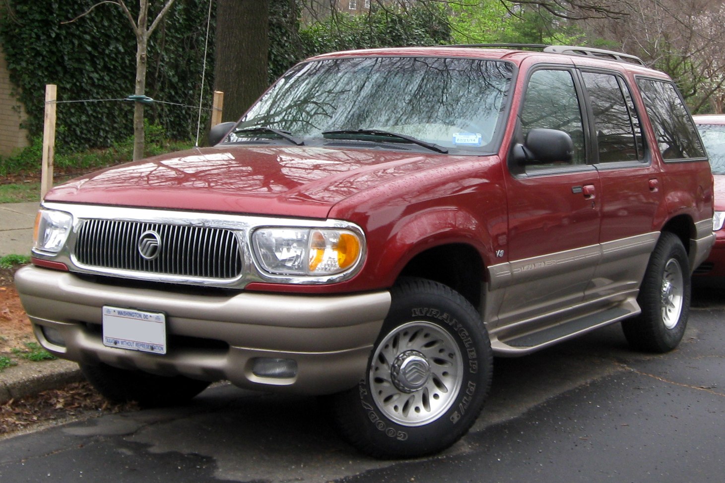 Front side view of a dual-tone SUV with classic grill and V8 badge