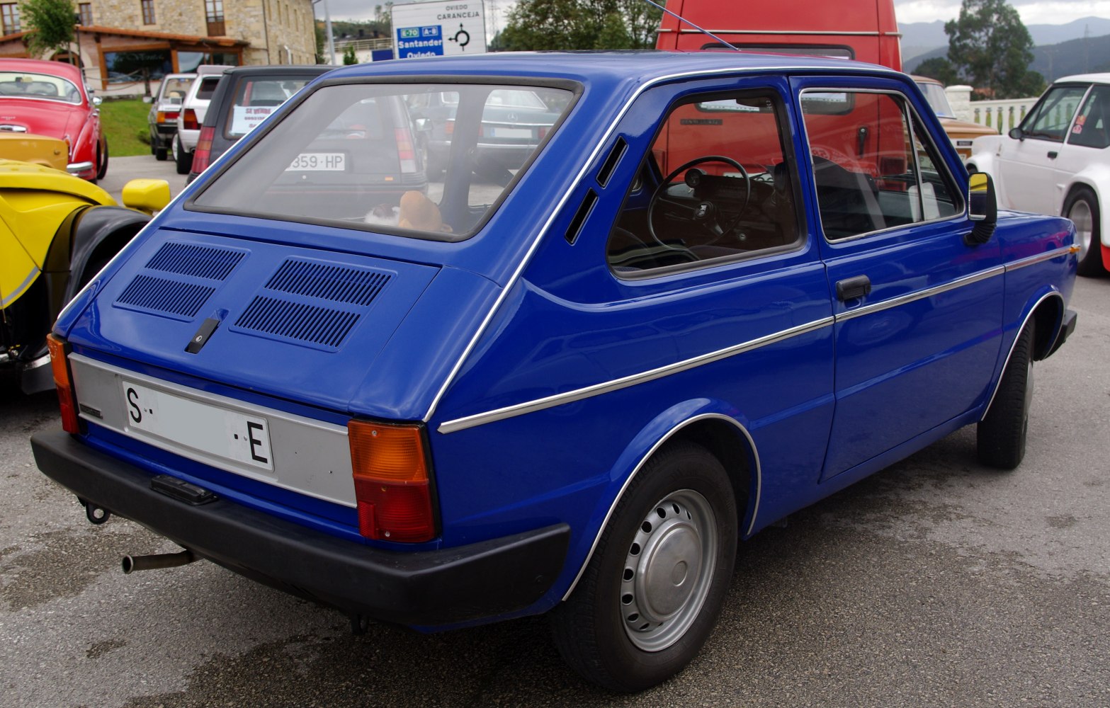 Rear view of blue vintage hatchback with rear ventilation panels.