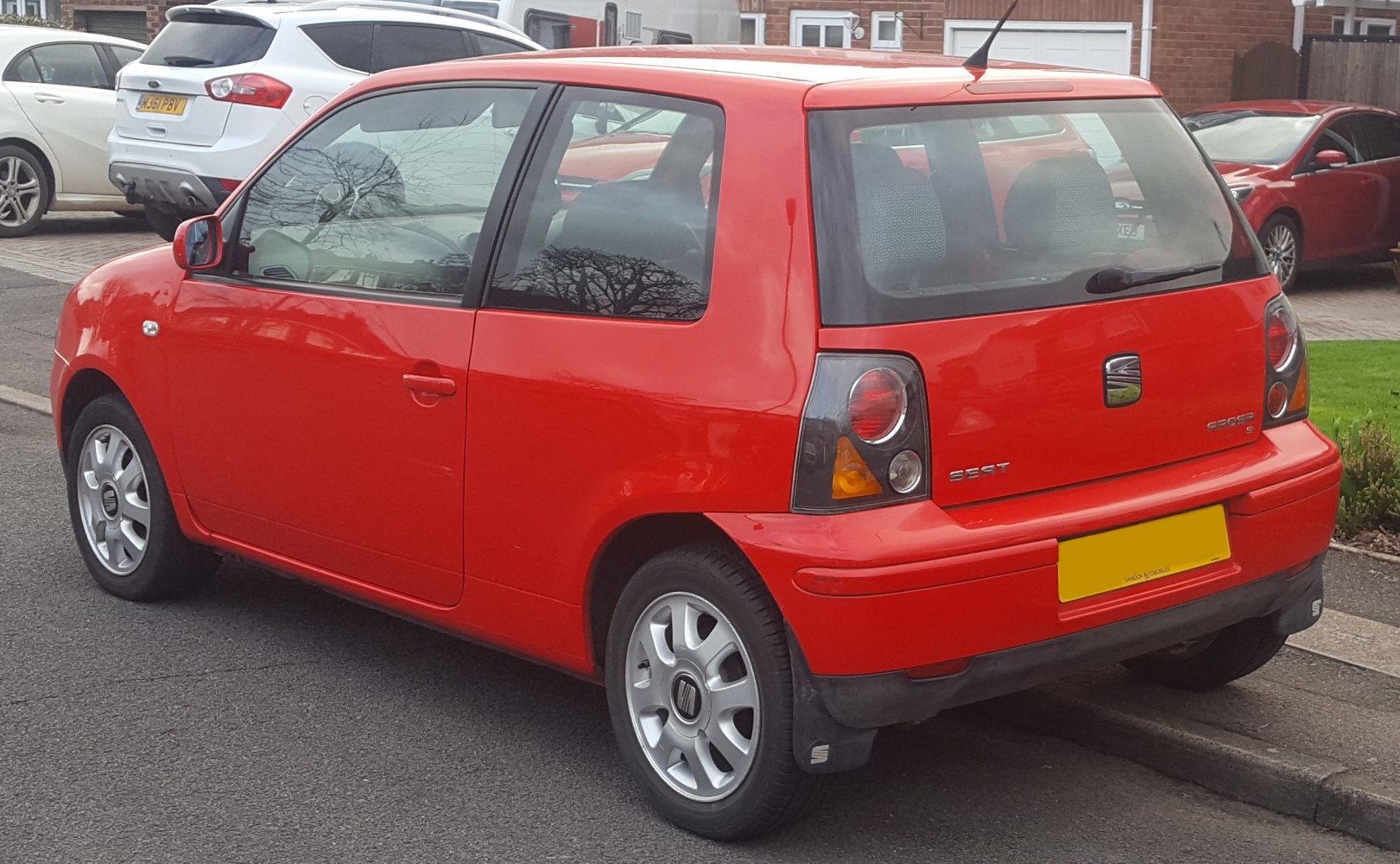 Rear-side view of red compact hatchback with facelift taillights and alloy wheels.