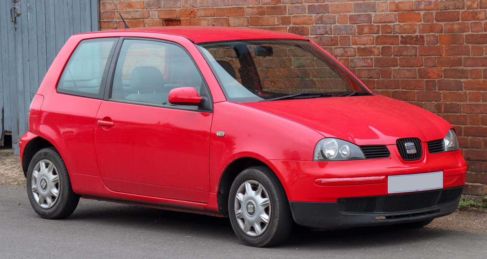 Red compact 3-door hatchback with distinct headlights and front side profile