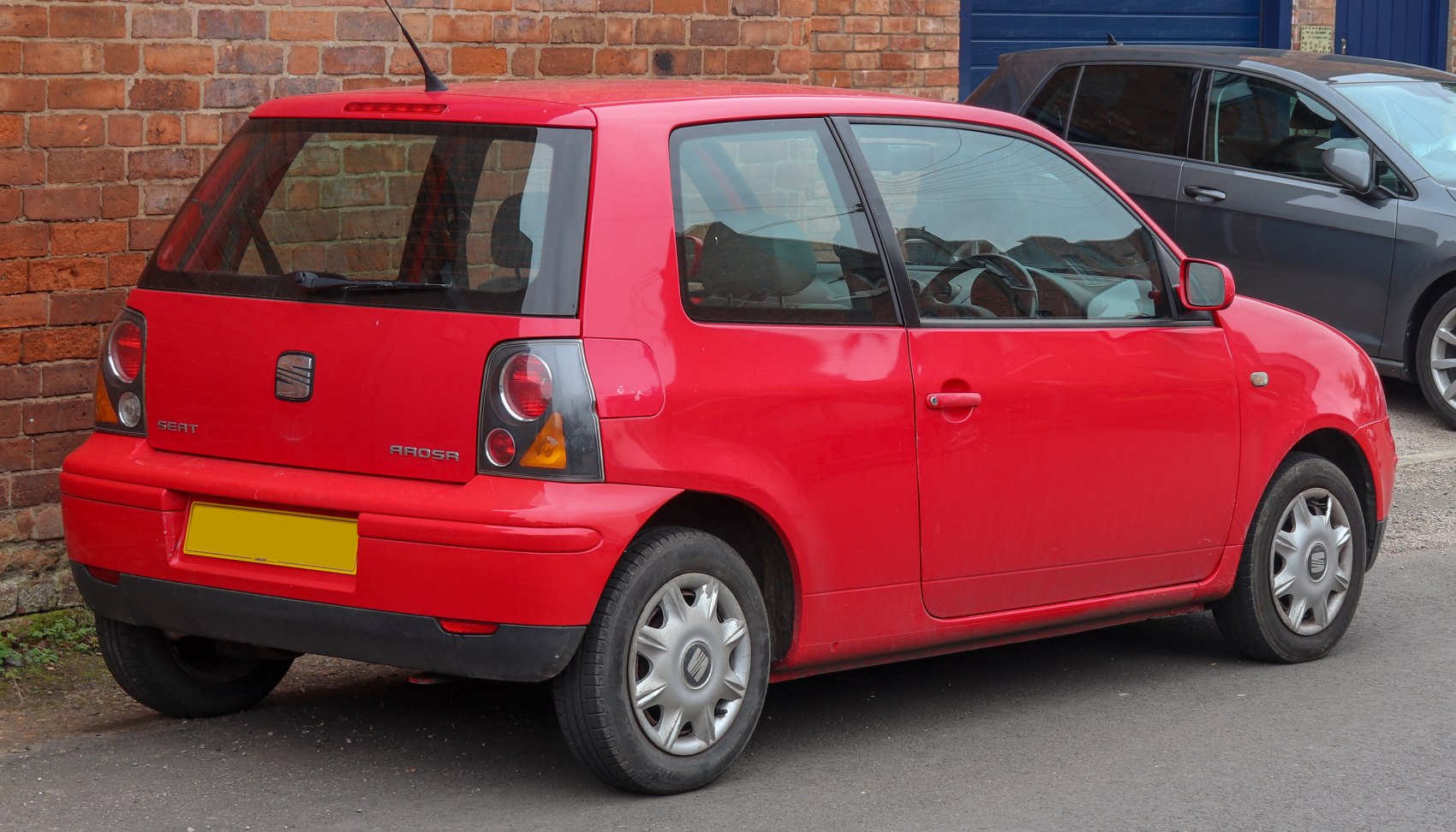 Rear and side view of a compact red hatchback with distinct tail lights