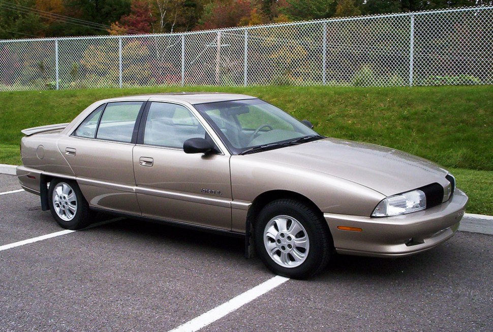 1992 beige sedan with rear spoiler and classic alloy wheels parked.