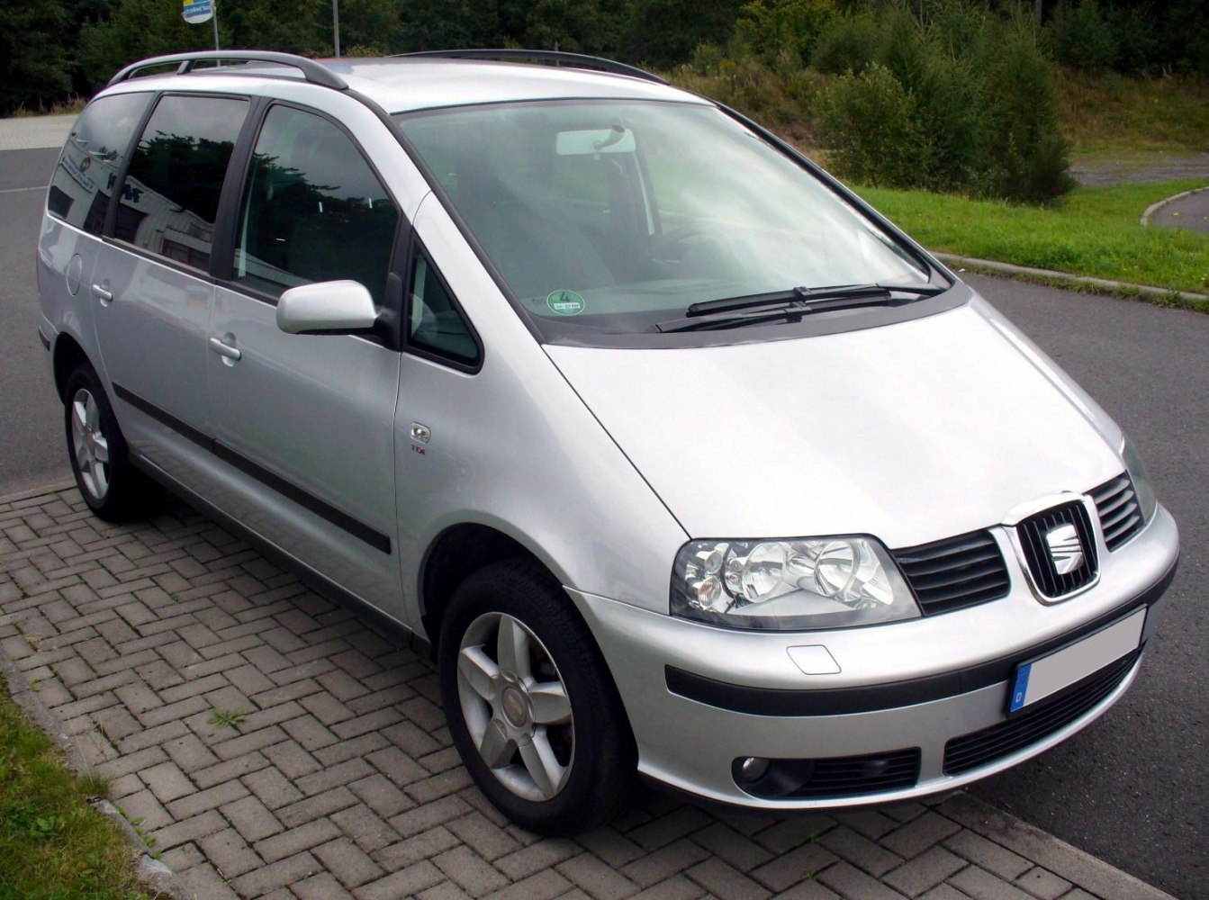 Silver multi-passenger family van with roof rails and alloy wheels