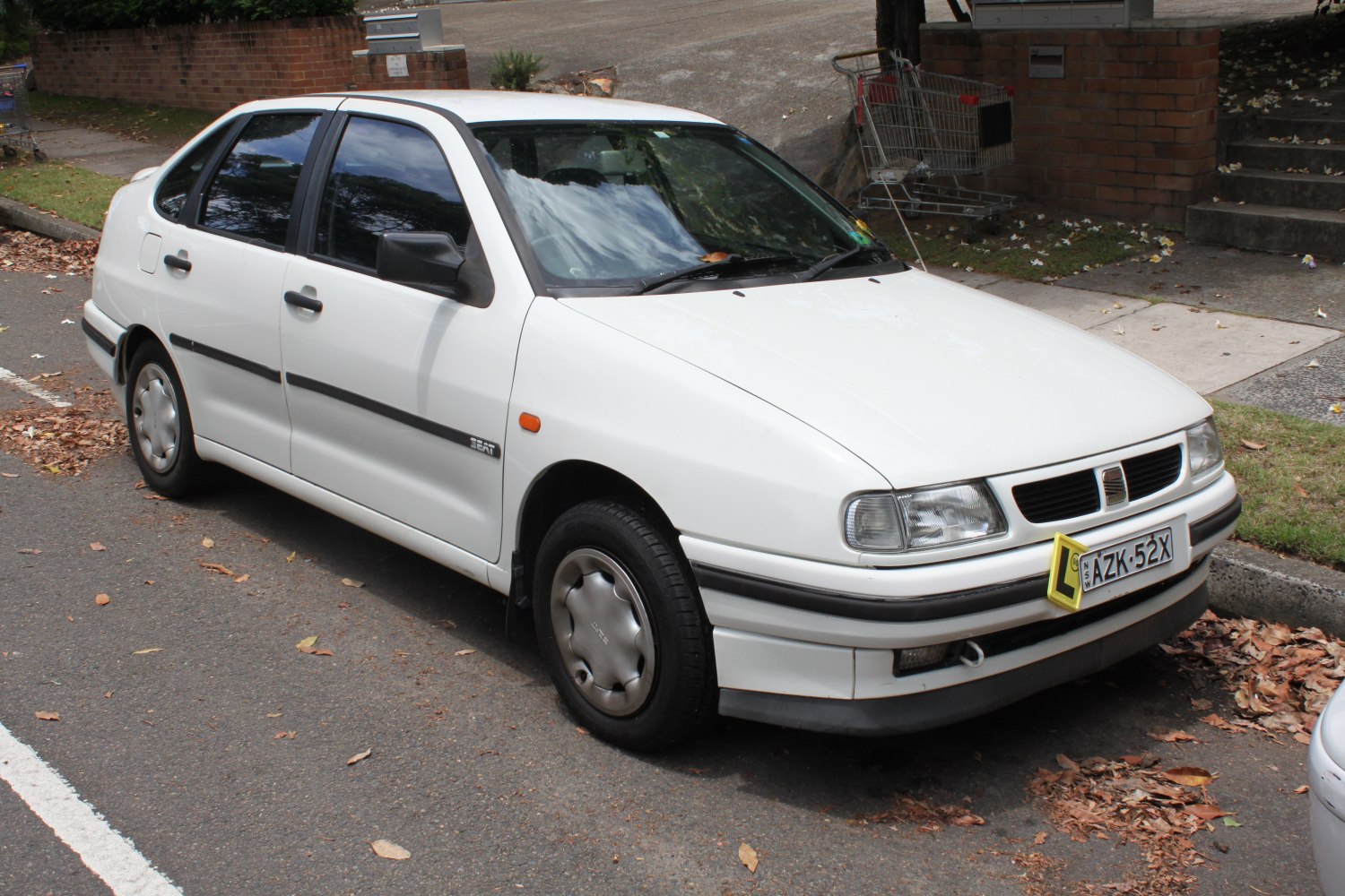 White compact sedan with 1990s styling and hubcaps