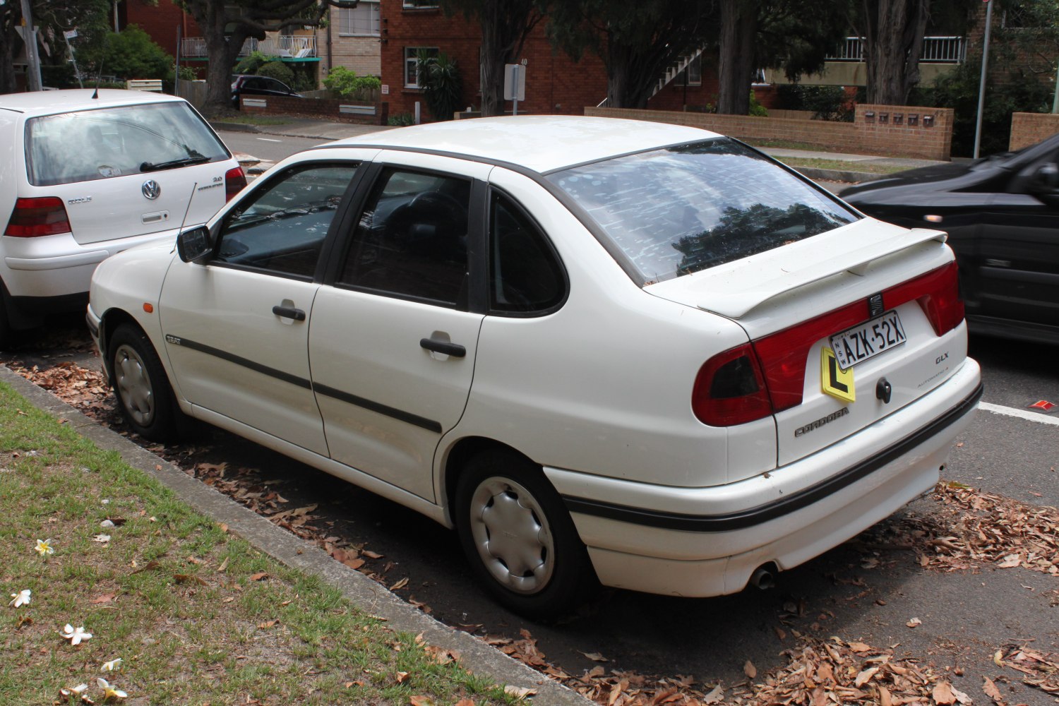 White compact sedan with rear spoiler and steel wheels