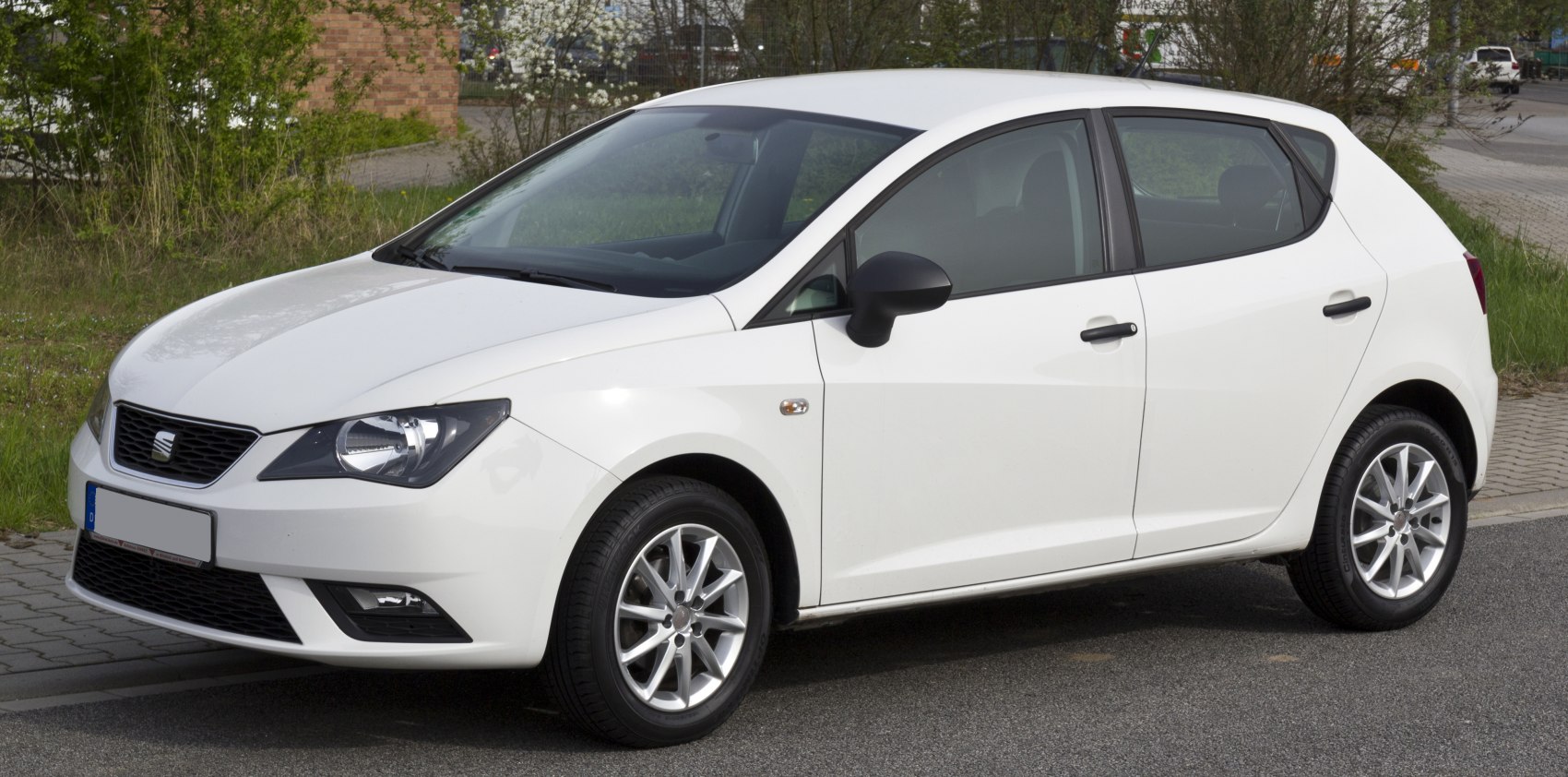 White hatchback front and side view with headlights and alloy wheels