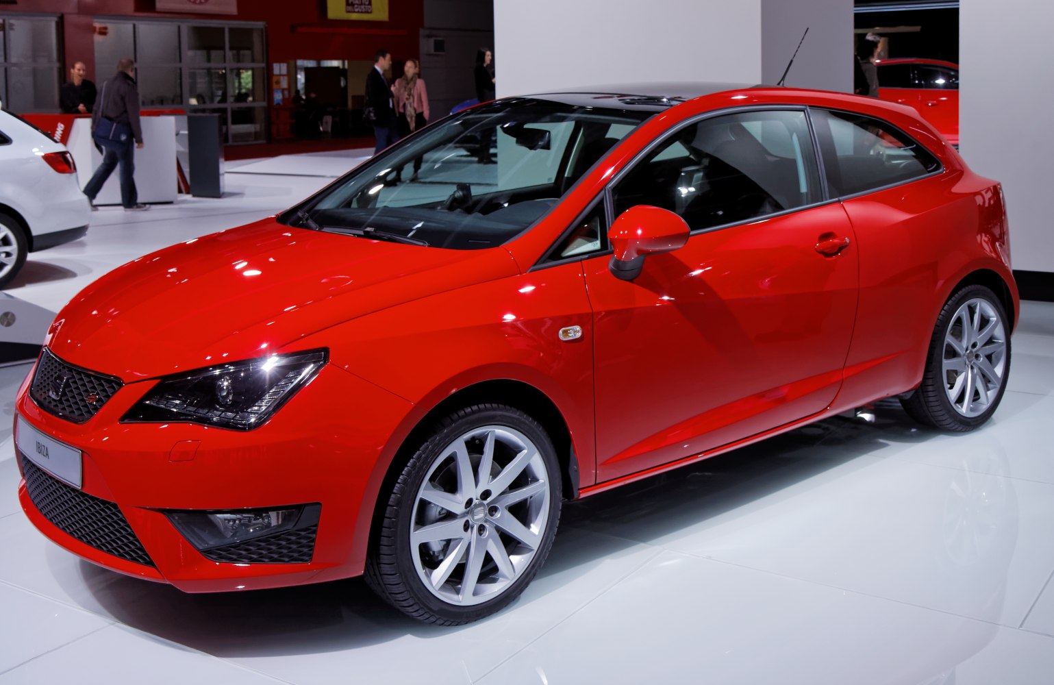 Sporty red 3-door hatchback with sleek headlights and alloy wheels