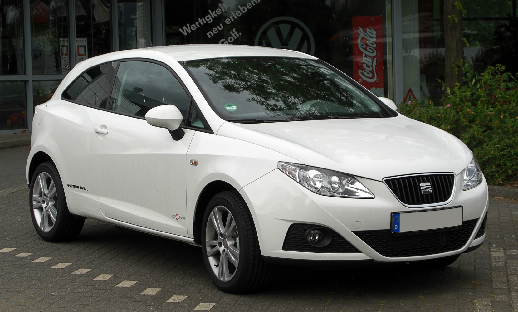 White hatchback front three-quarter view with headlights and alloy wheels