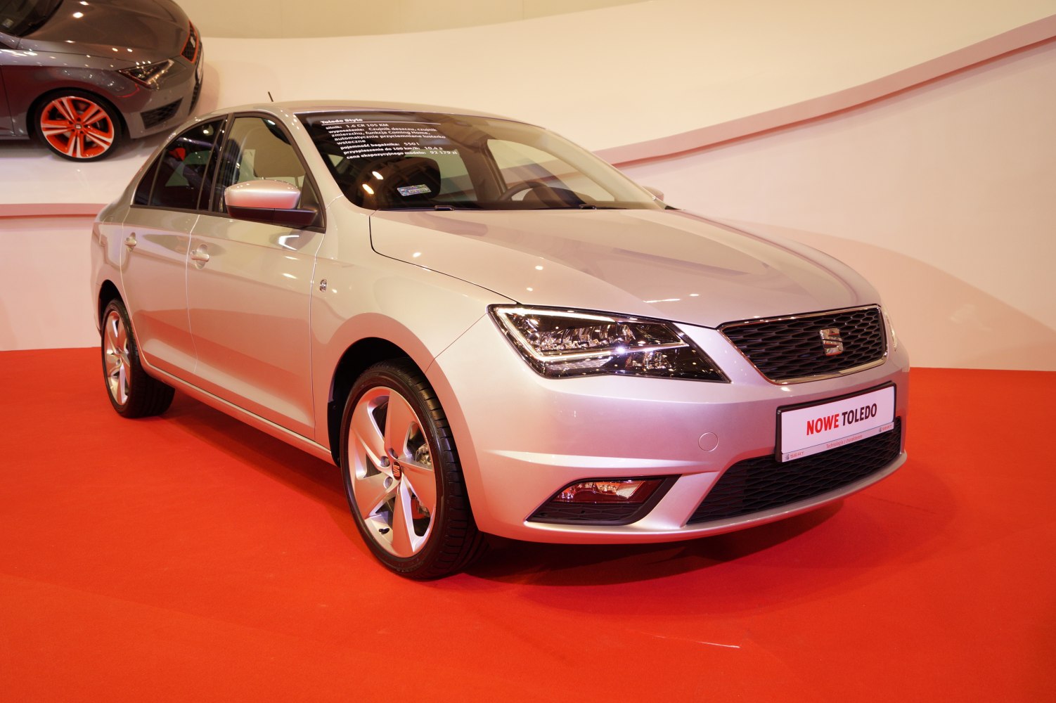 Silver sedan front side with alloy wheels on red floor