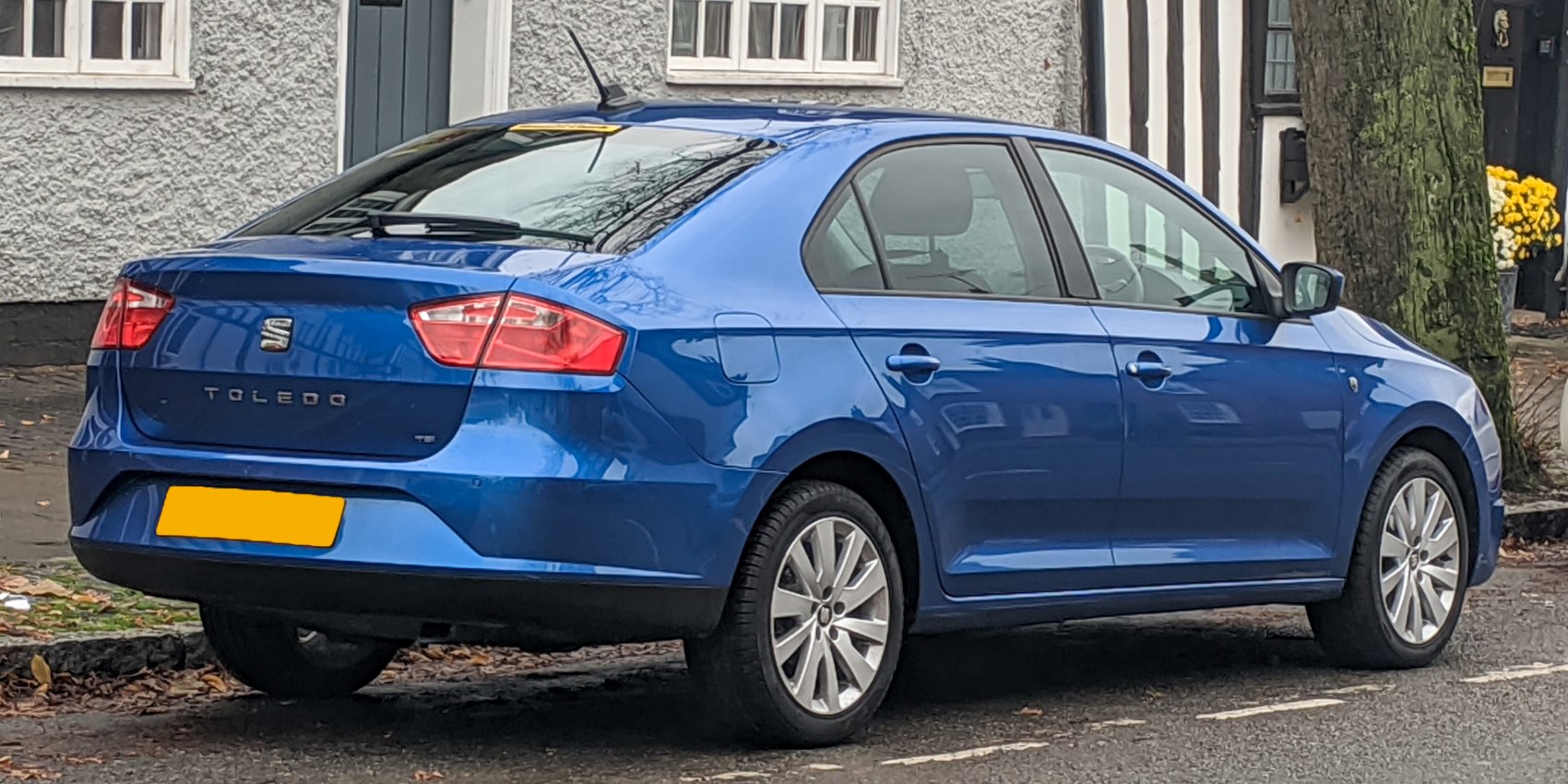 Blue compact sedan with rear spoiler and alloy wheels