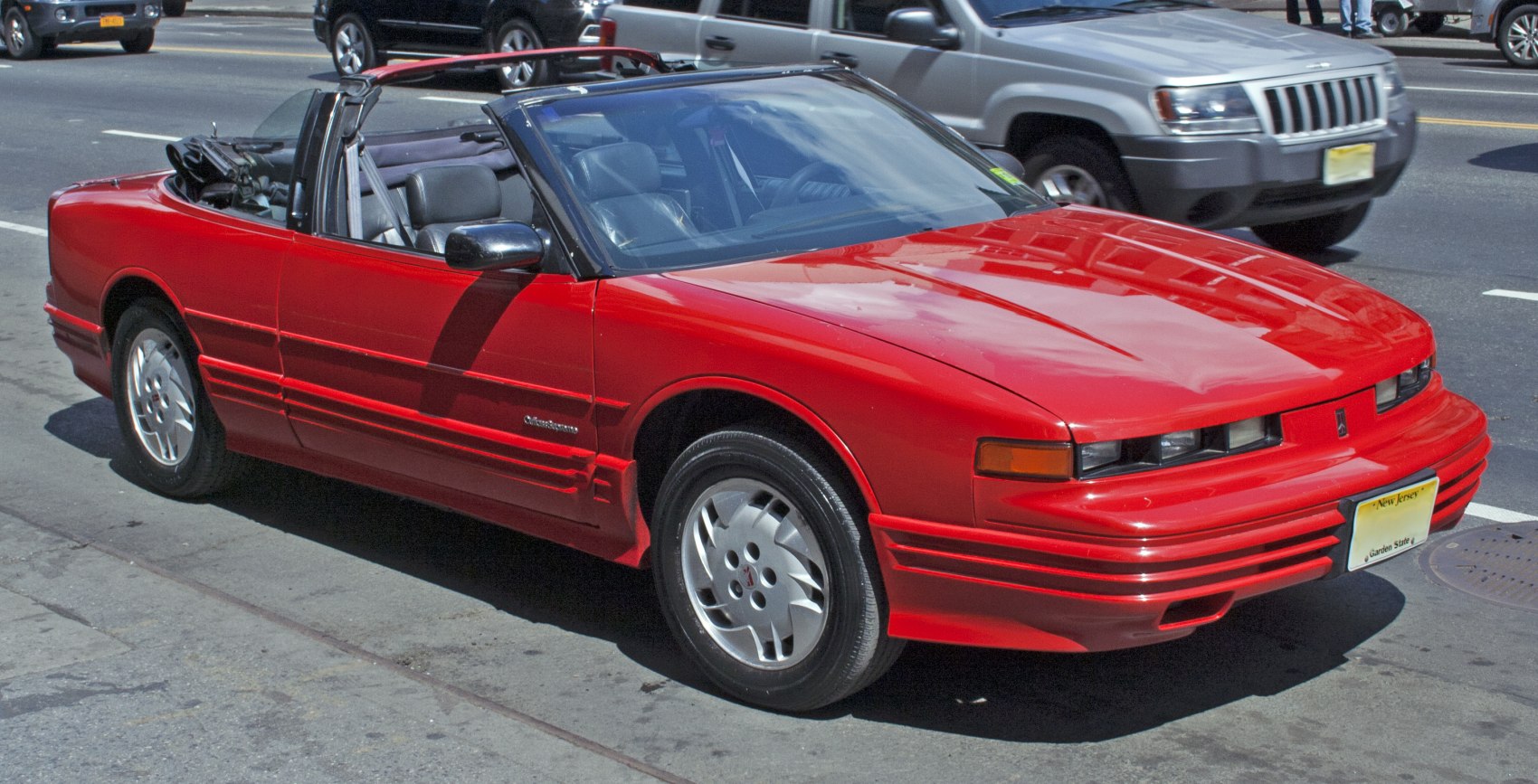Red convertible car with retractable roof open showing front side