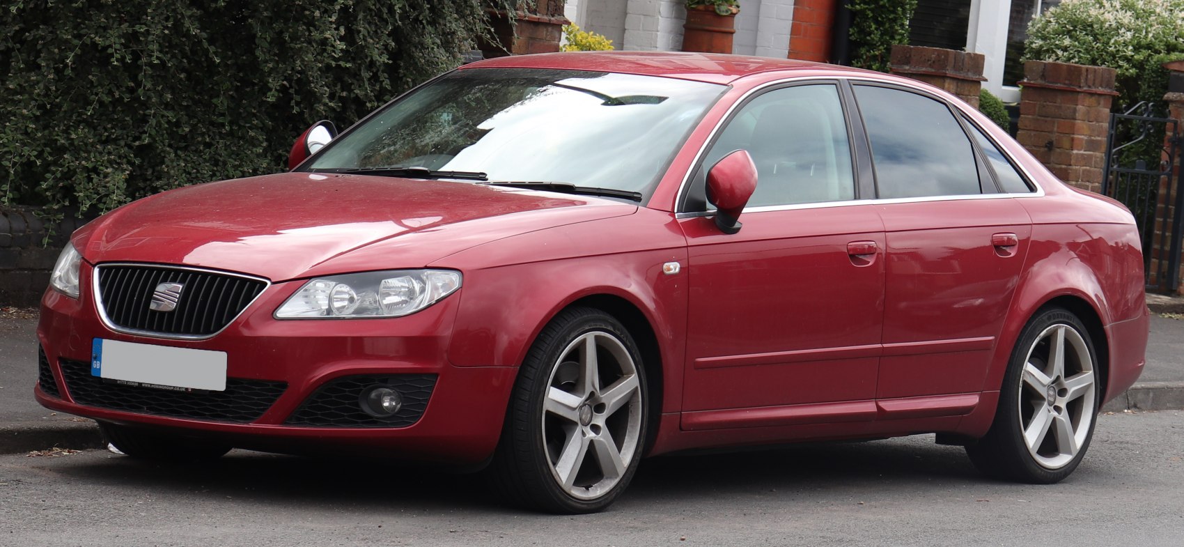 Red sedan front-side view with alloy wheels and fog lights