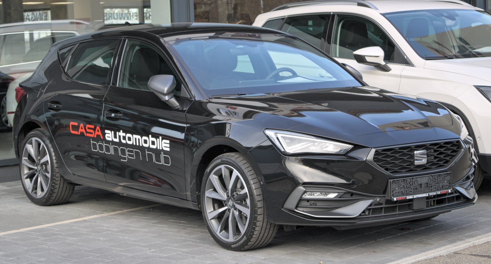Front three-quarter view of a sporty black hatchback with sharp headlights and alloy wheels.