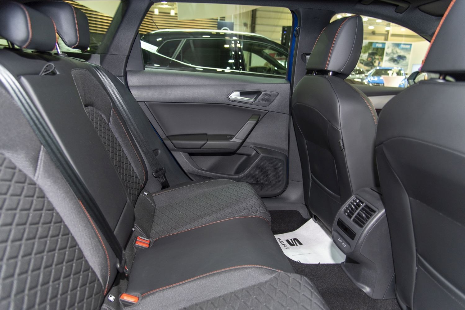 Rear seating with quilted black upholstery, orange stitching, and rear ventilation