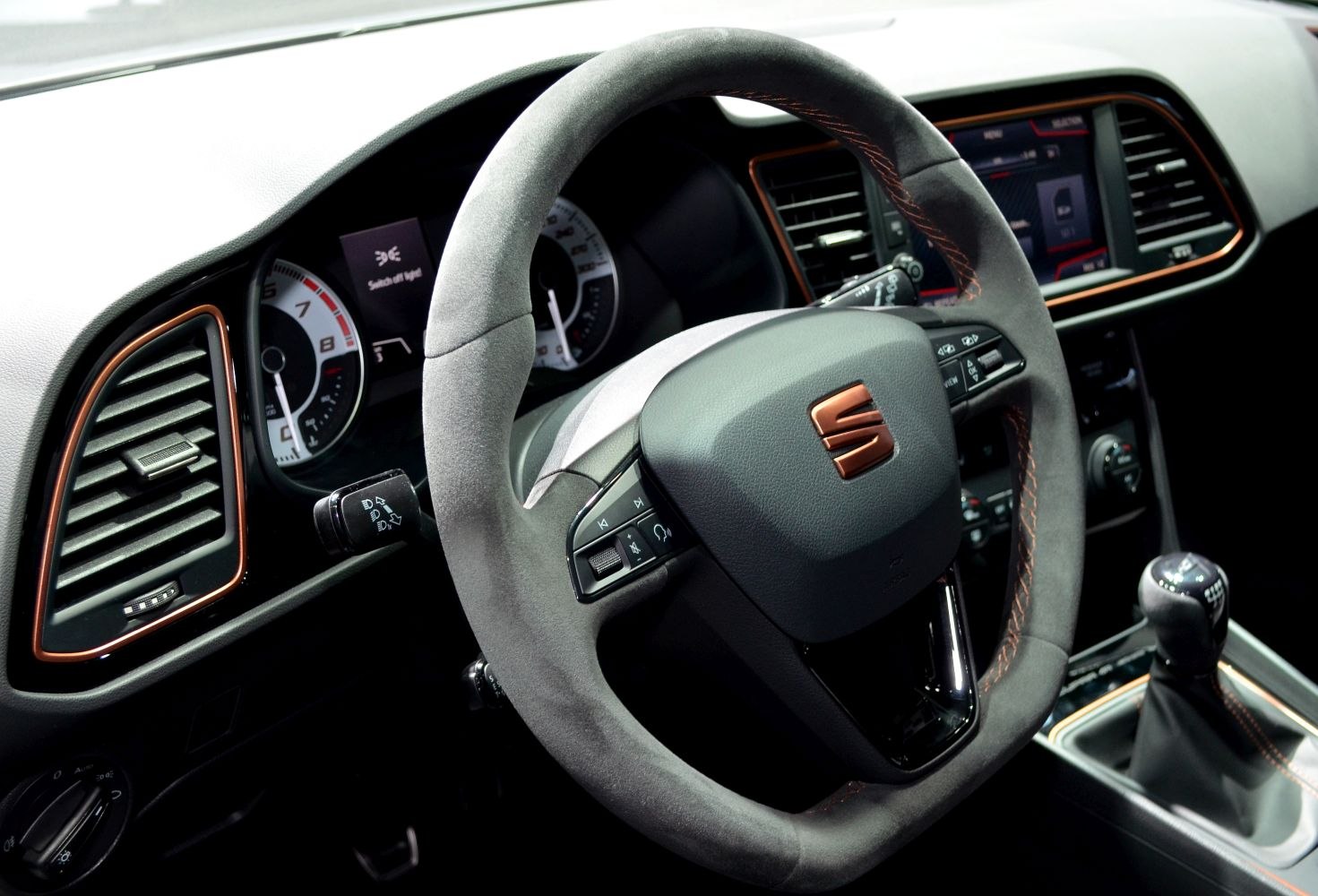 Steering wheel and manual gear shift with dashboard and control buttons in black and copper accents