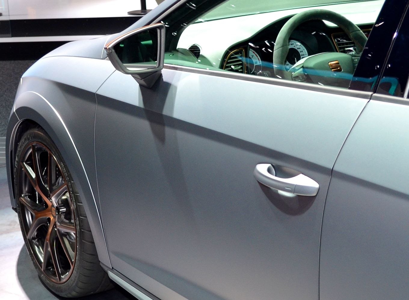 Car side door with handle, alloy wheel, steering wheel and instrument cluster visible