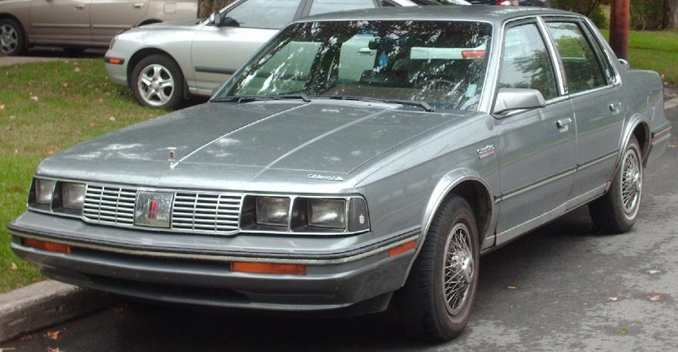 Front three-quarter view of sedan with rectangular headlights and wire-spoke wheels