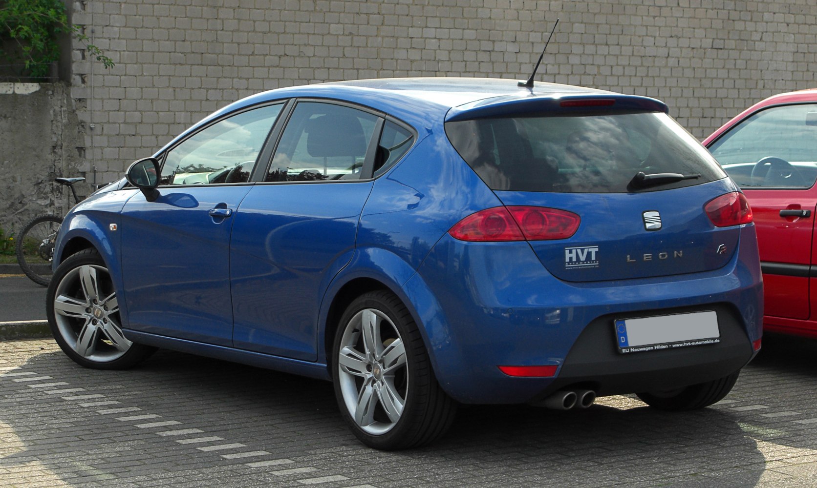 Rear and side view of a blue hatchback with sporty alloy wheels and dual exhaust