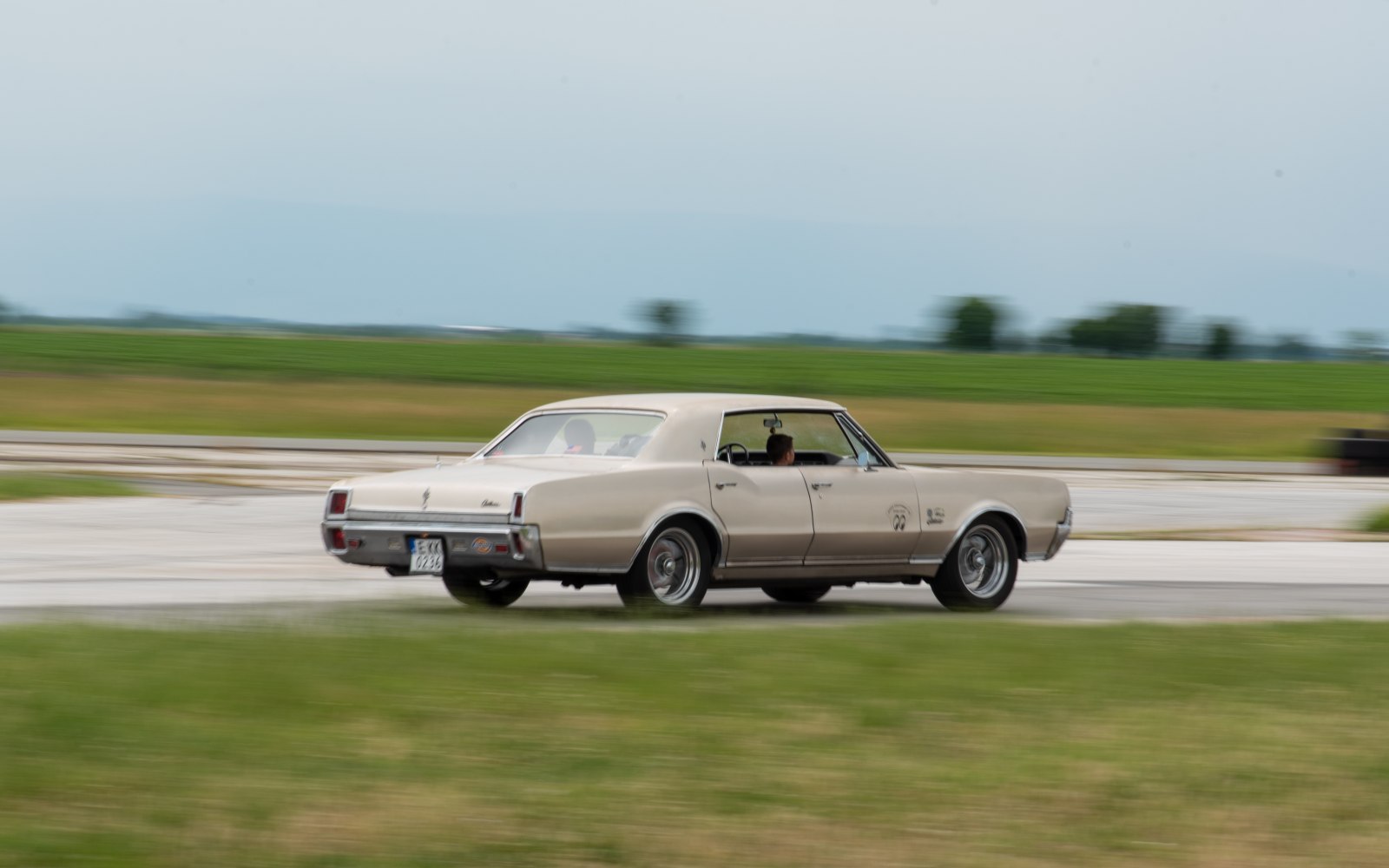 Rear-side view of a vintage sedan in motion with motion blur
