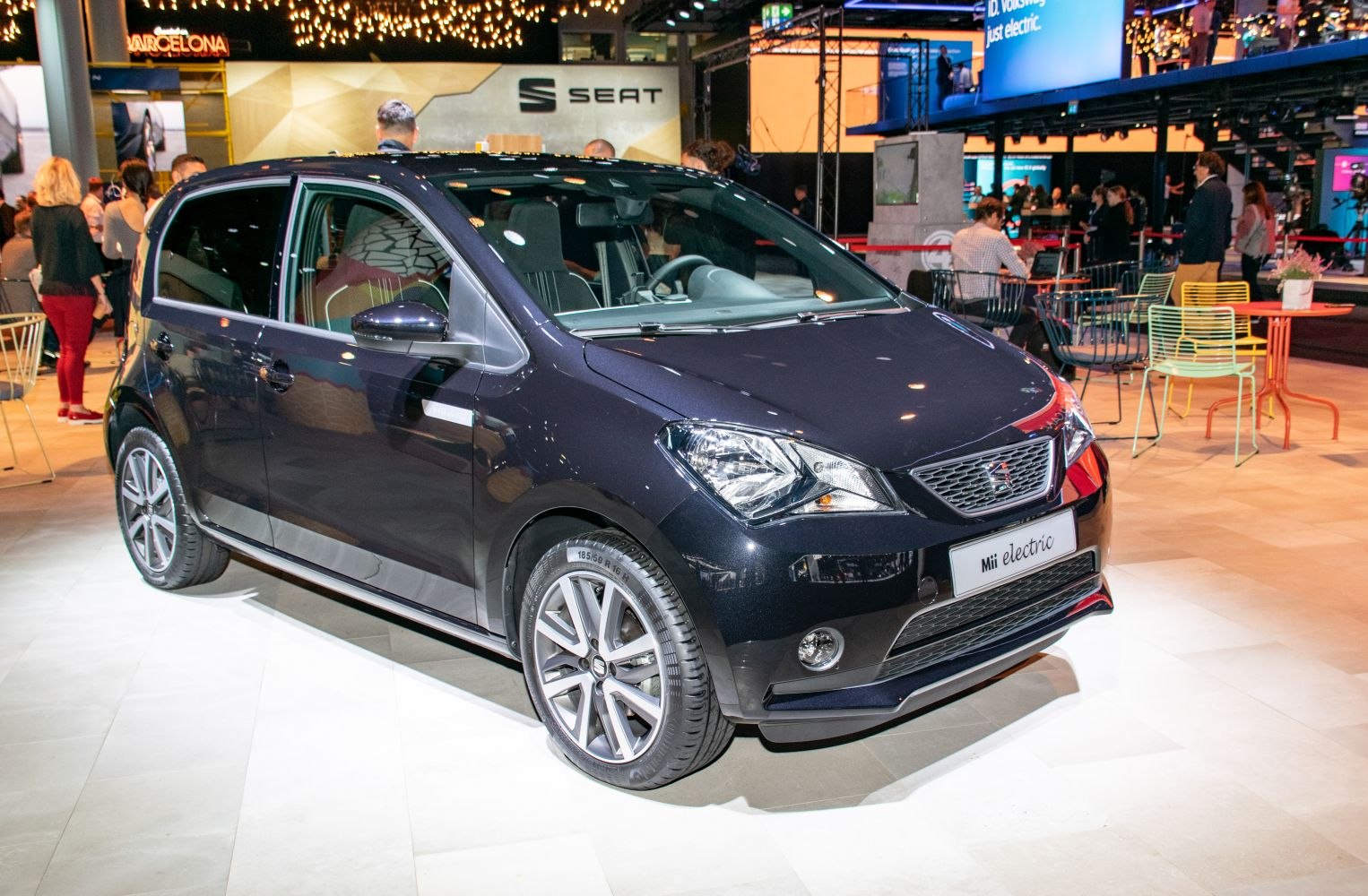 Compact electric hatchback in showroom with distinct headlight and alloy wheel design