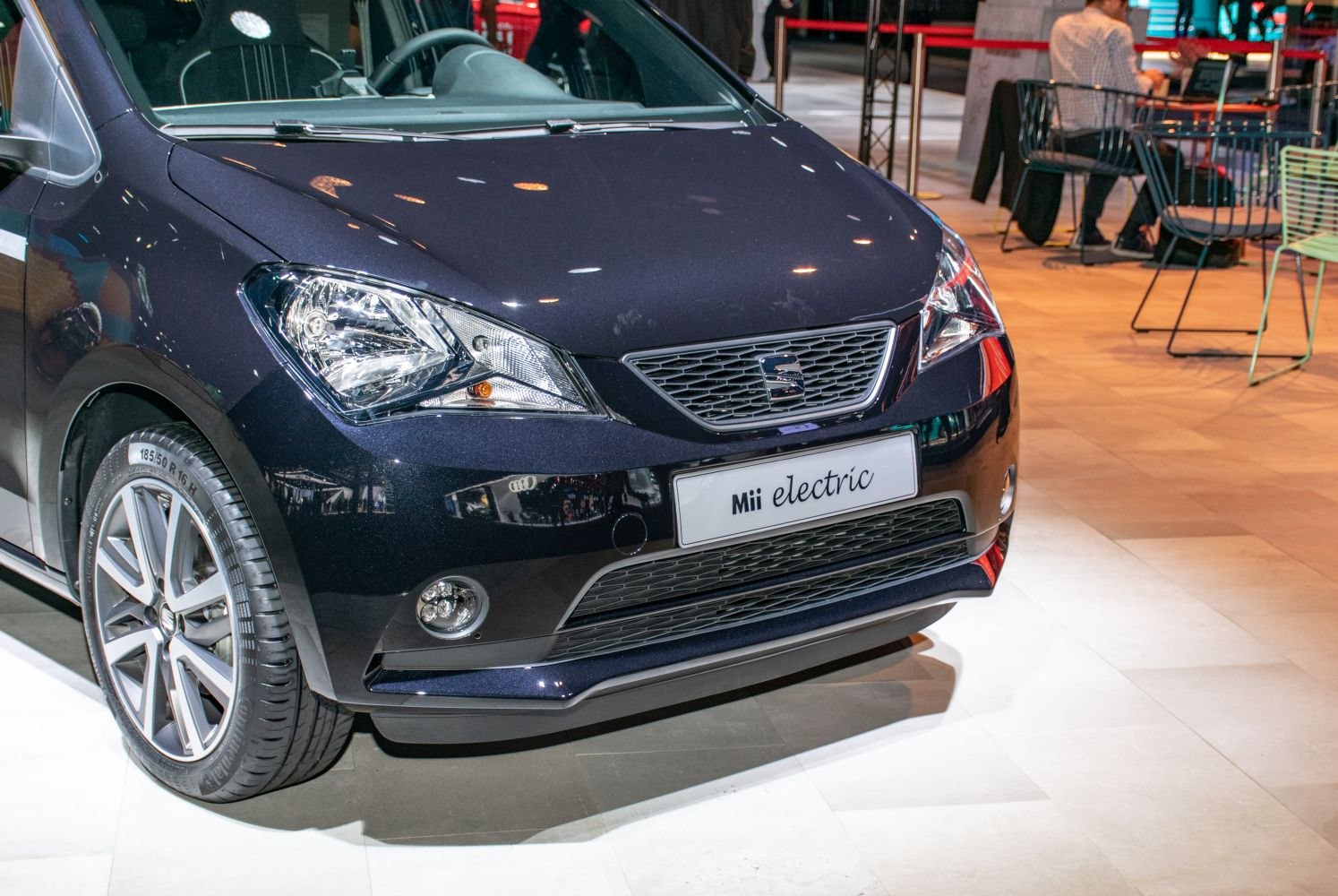 Close-up of front grille, headlights, and wheel of a compact electric vehicle.
