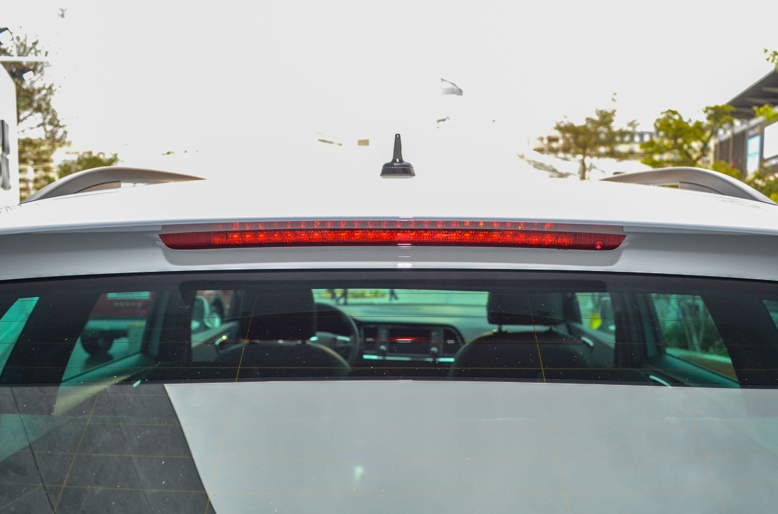 Rear window with roof antenna and integrated brake light