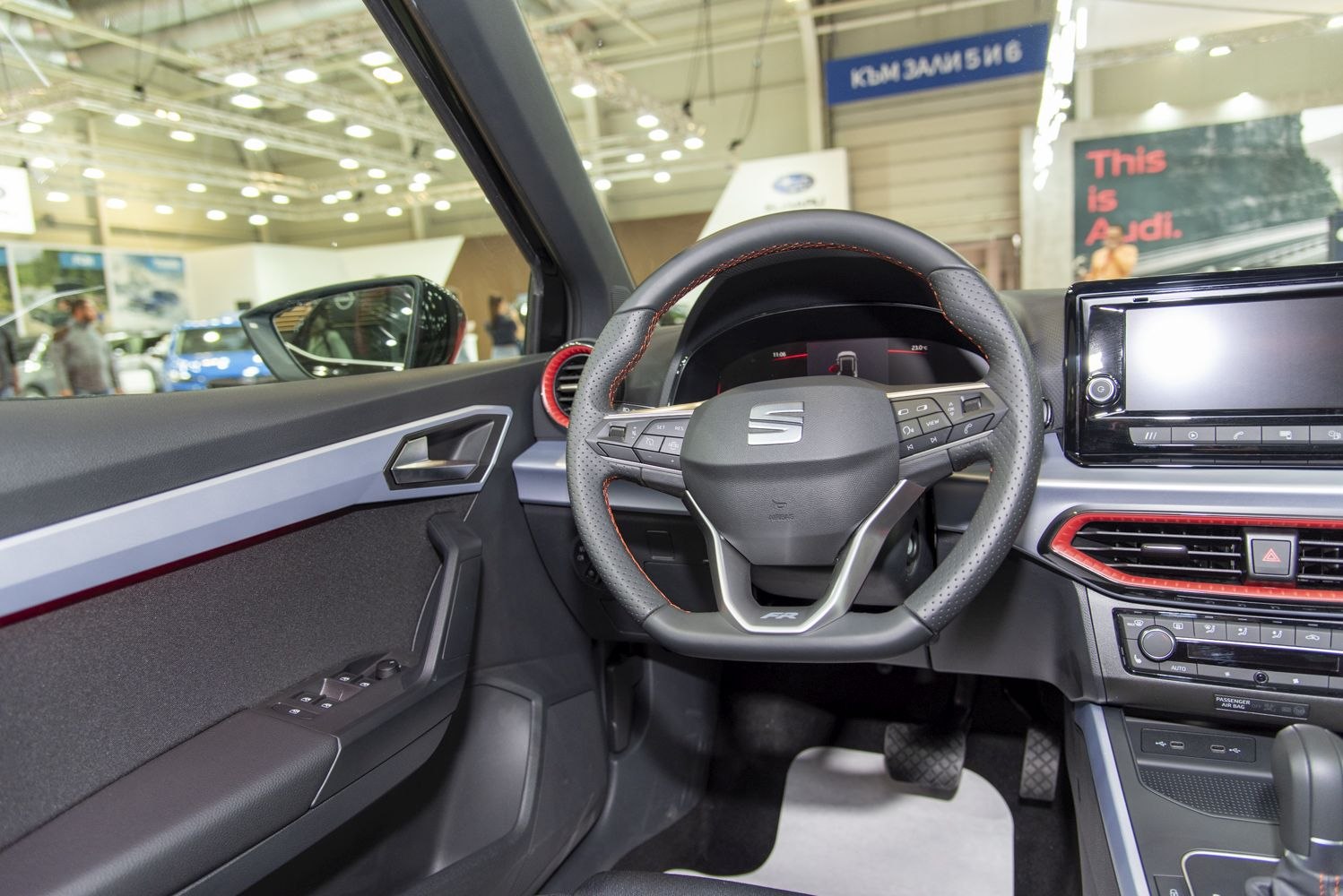 Car steering wheel and dashboard with door panel and controls.